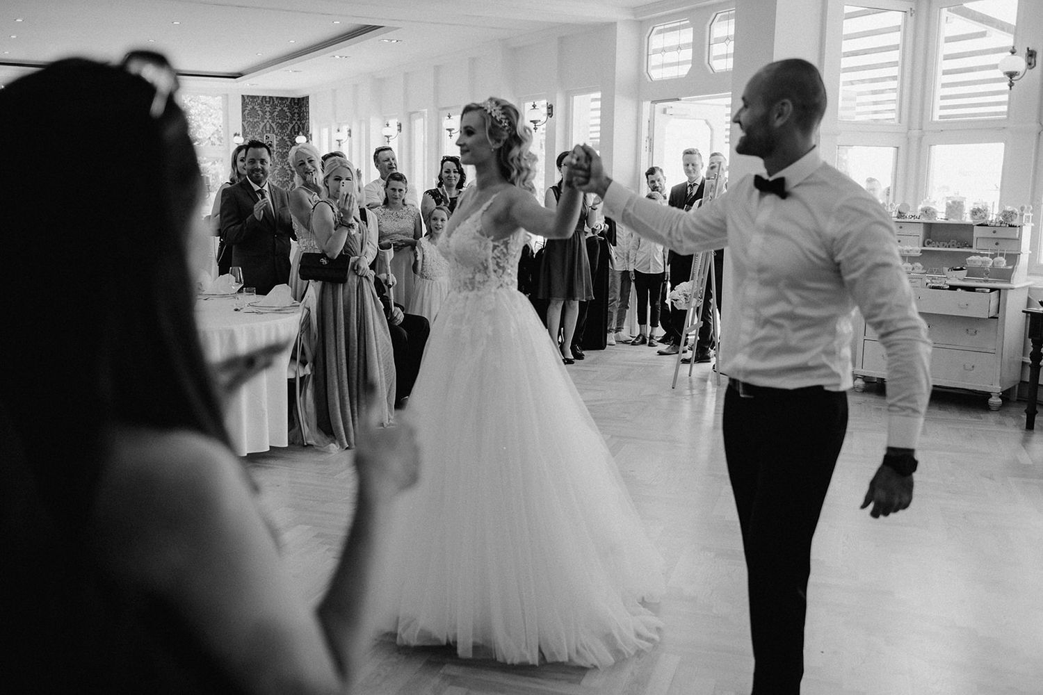 Bride in white ball gown and groom in tuxedo share first dance at wedding reception.