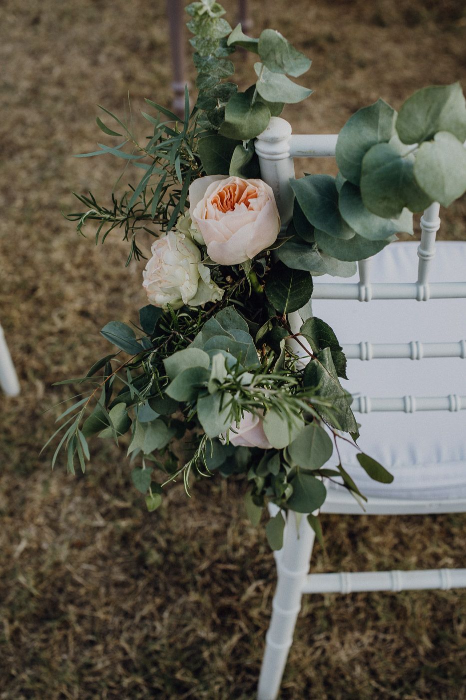 Blush garden roses and eucalyptus floral arrangement decorating a white chiavari wedding chair. Tuscany Villa Catignano