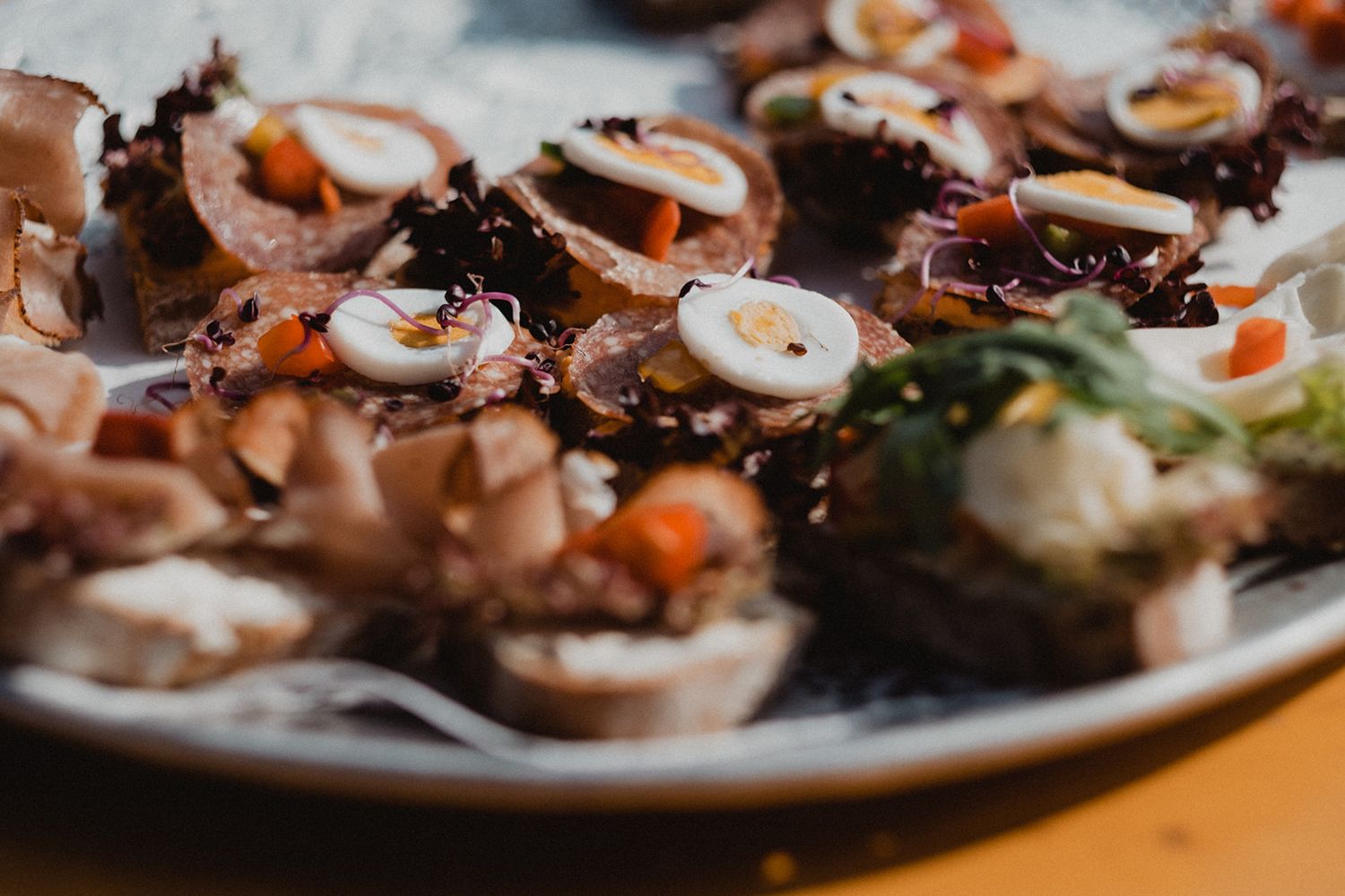 Close-up of elegant appetizers topped with sliced mushrooms and colorful vegetables on a decorative plate at a wedding reception. Jufenalm