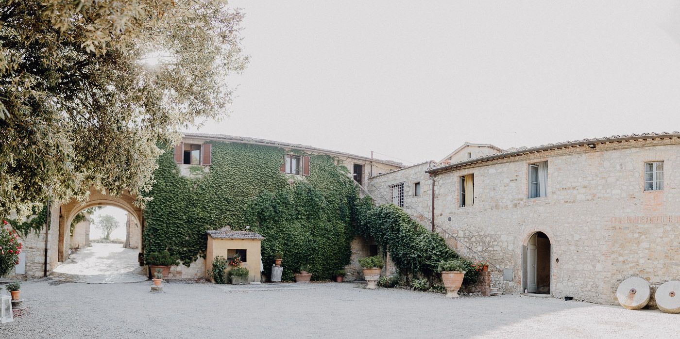 Charming Italian stone farmhouse courtyard covered in ivy with terracotta pots and arched entrance. Tuscany Villa Catignano