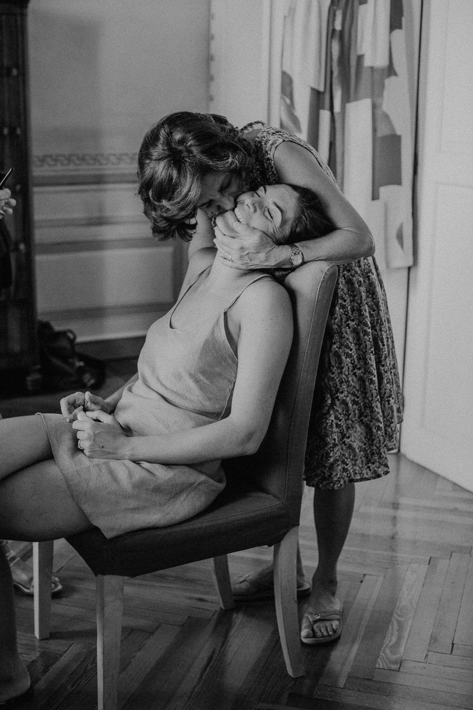 Emotional black and white photo of a woman embracing a seated bride tenderly before the wedding. Tuscany Villa Catignano