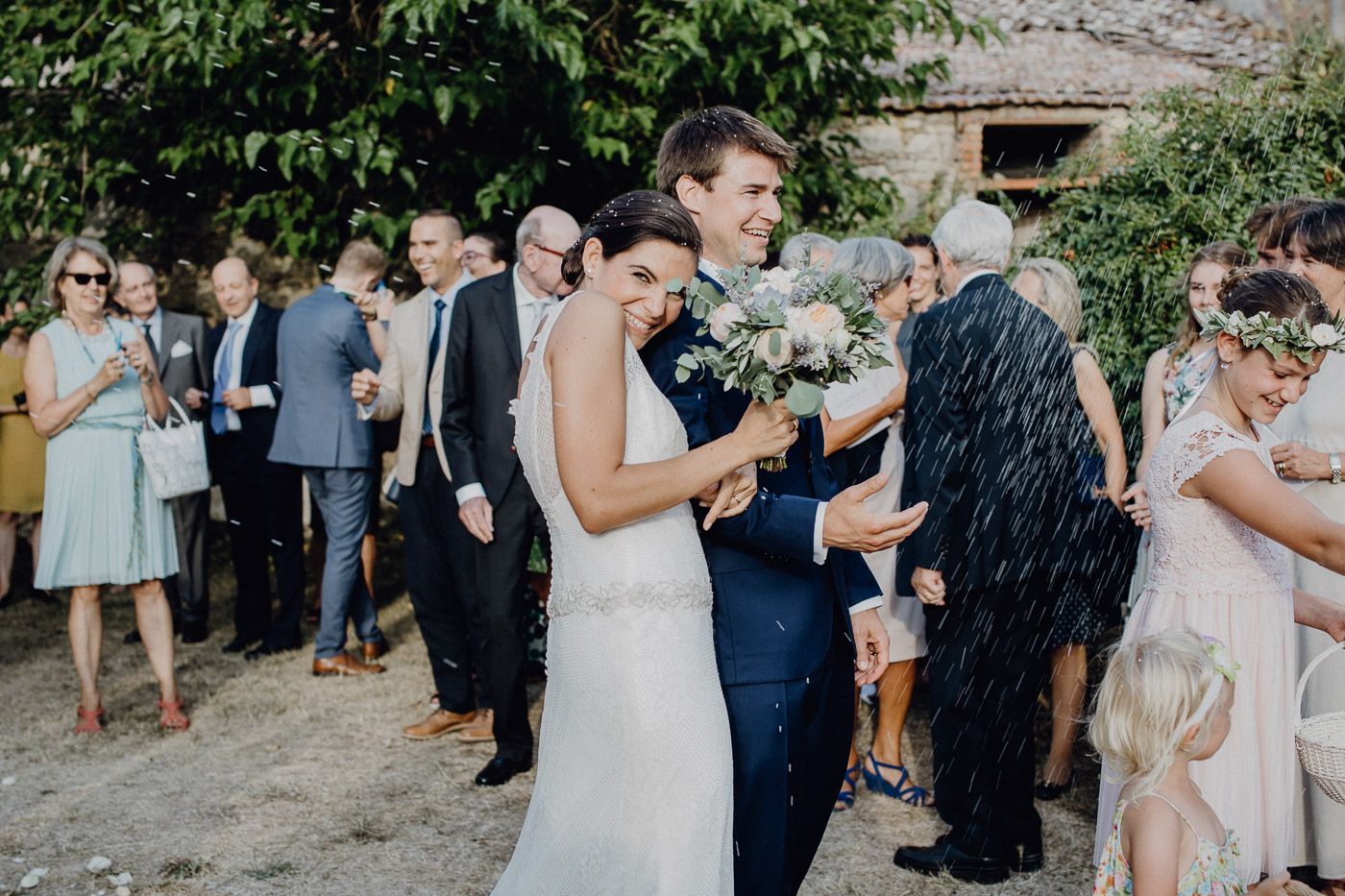 Bride and groom celebrate with guests as champagne is sprayed at joyful outdoor wedding reception. Tuscany Villa Catignano