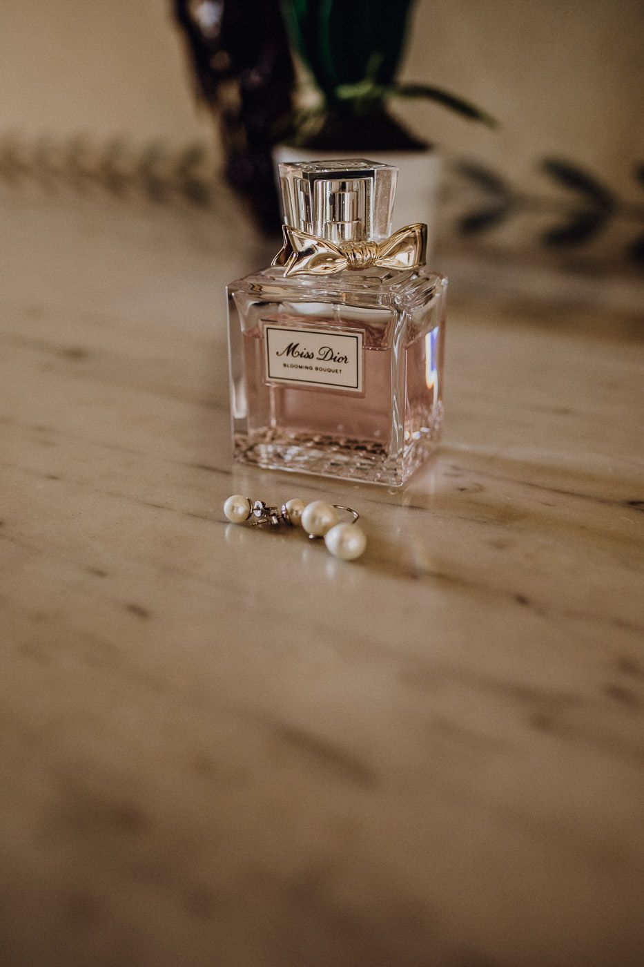 Miss Dior Blooming Bouquet perfume bottle with pearl drop earrings on a marble surface. Tuscany Villa Catignano
