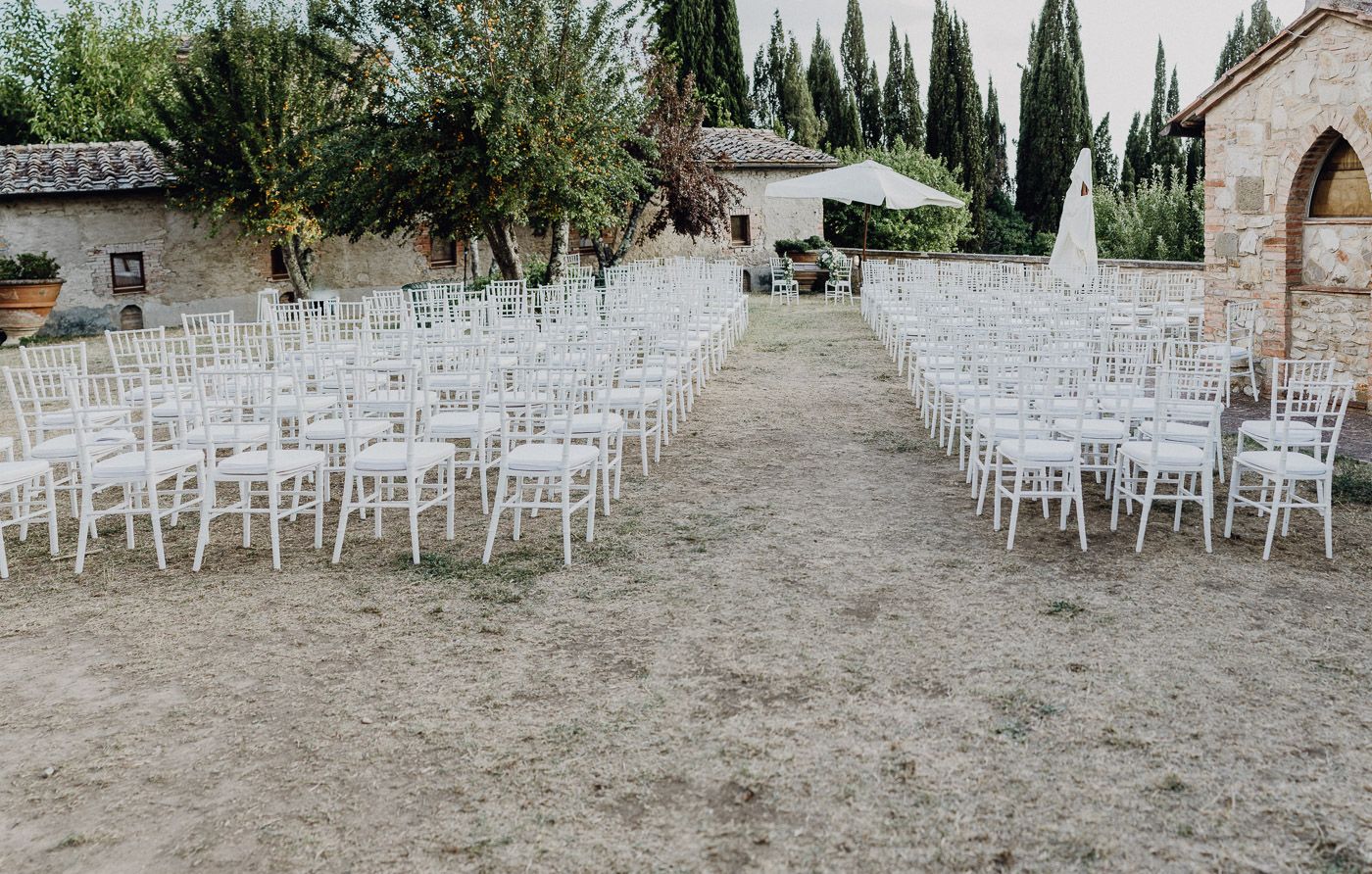 Rows of white chiavari chairs set for an outdoor wedding ceremony at a Tuscan villa. Tuscany Villa Catignano