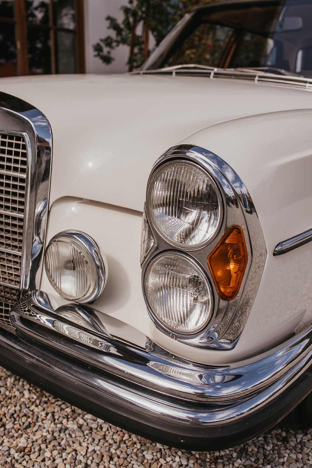 Close-up of a classic vintage white Mercedes-Benz car showcasing chrome headlights and bumper details.