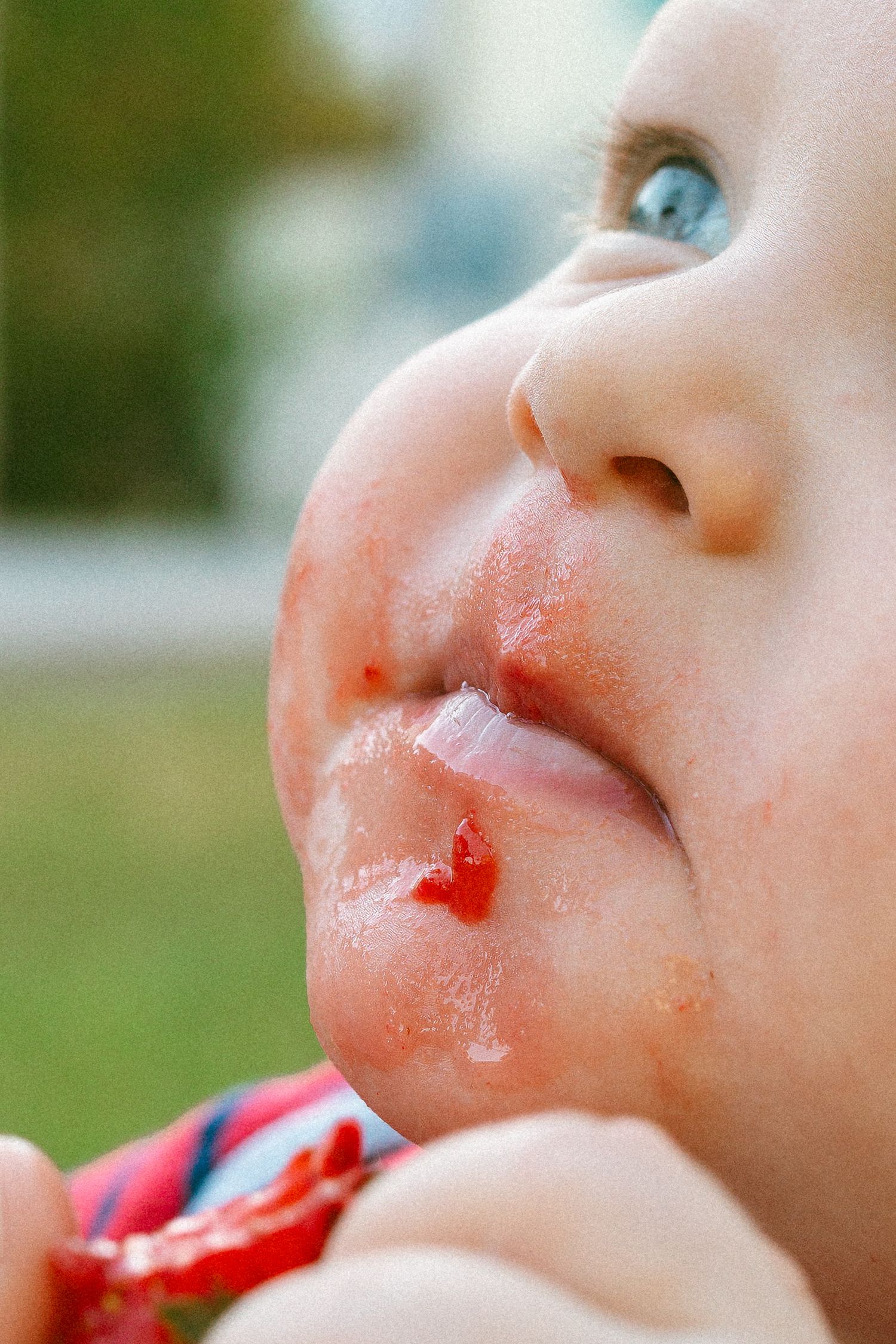 baby with strawberry juice running down chin