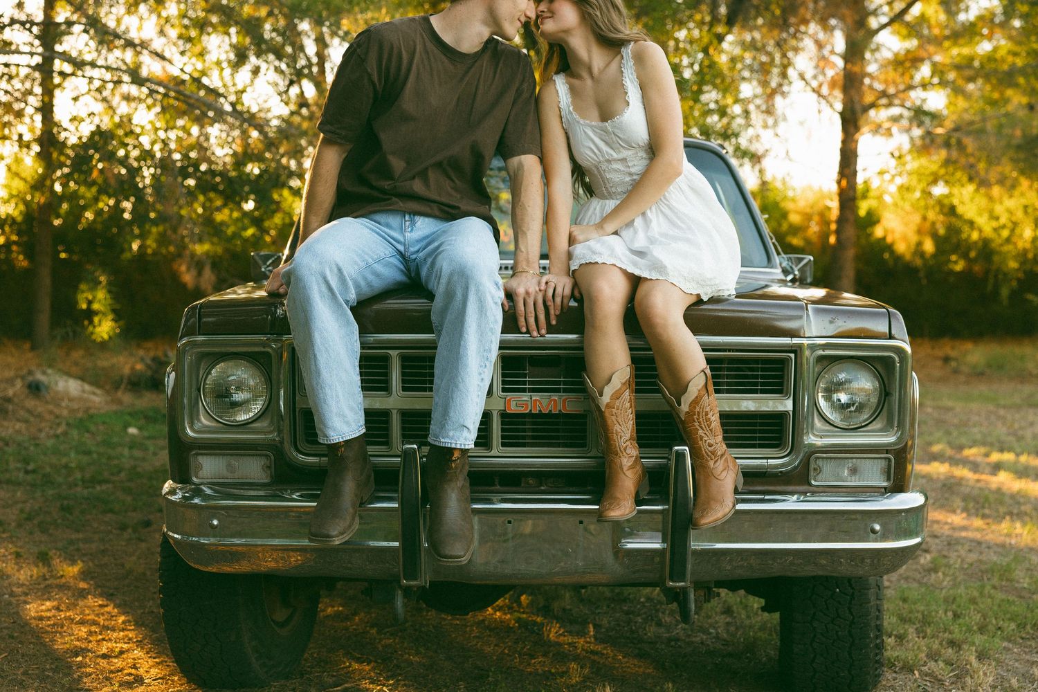 couple sitting on an old truck in a meadow at a couples photo session