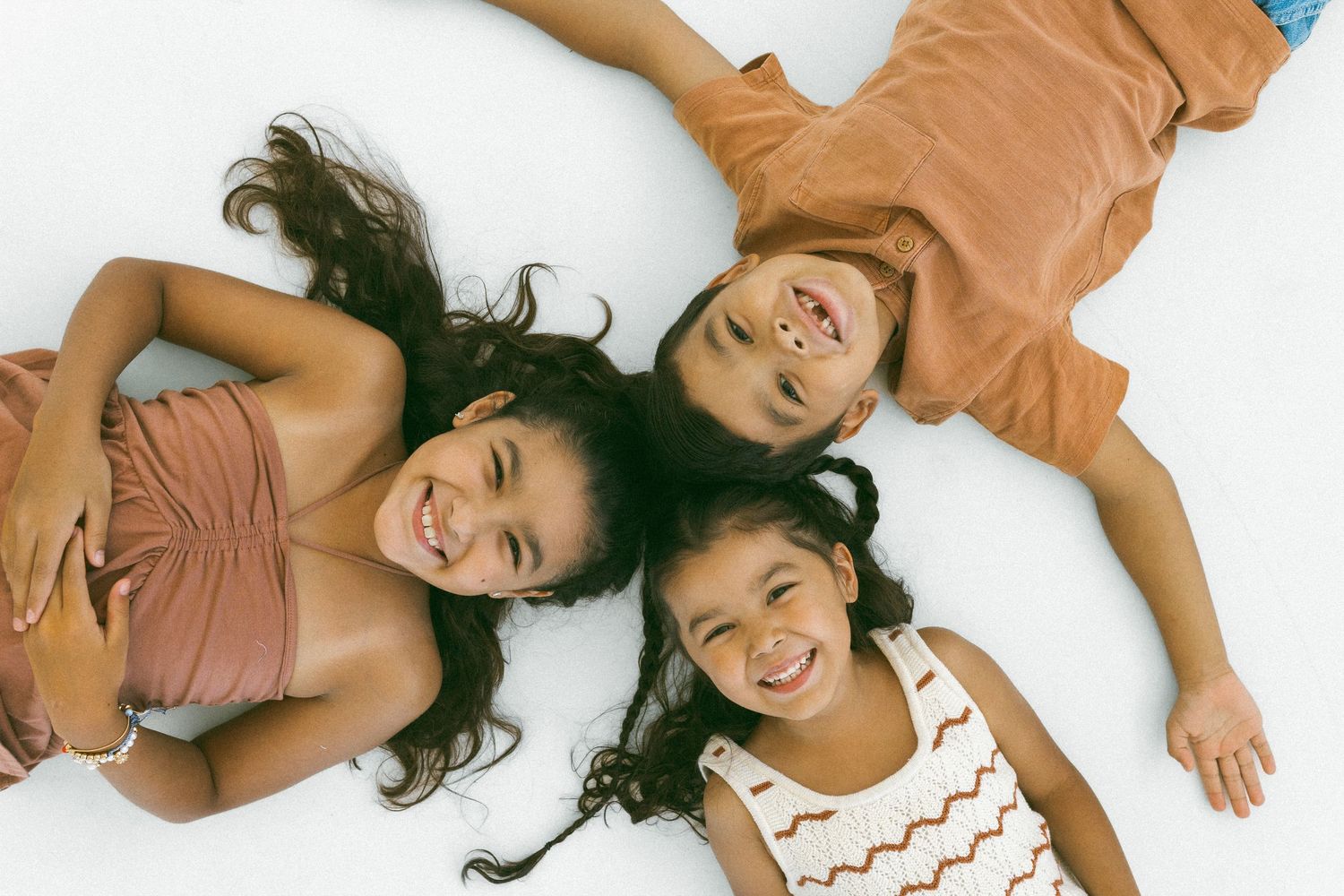 three children smiling at the camera during a mini session