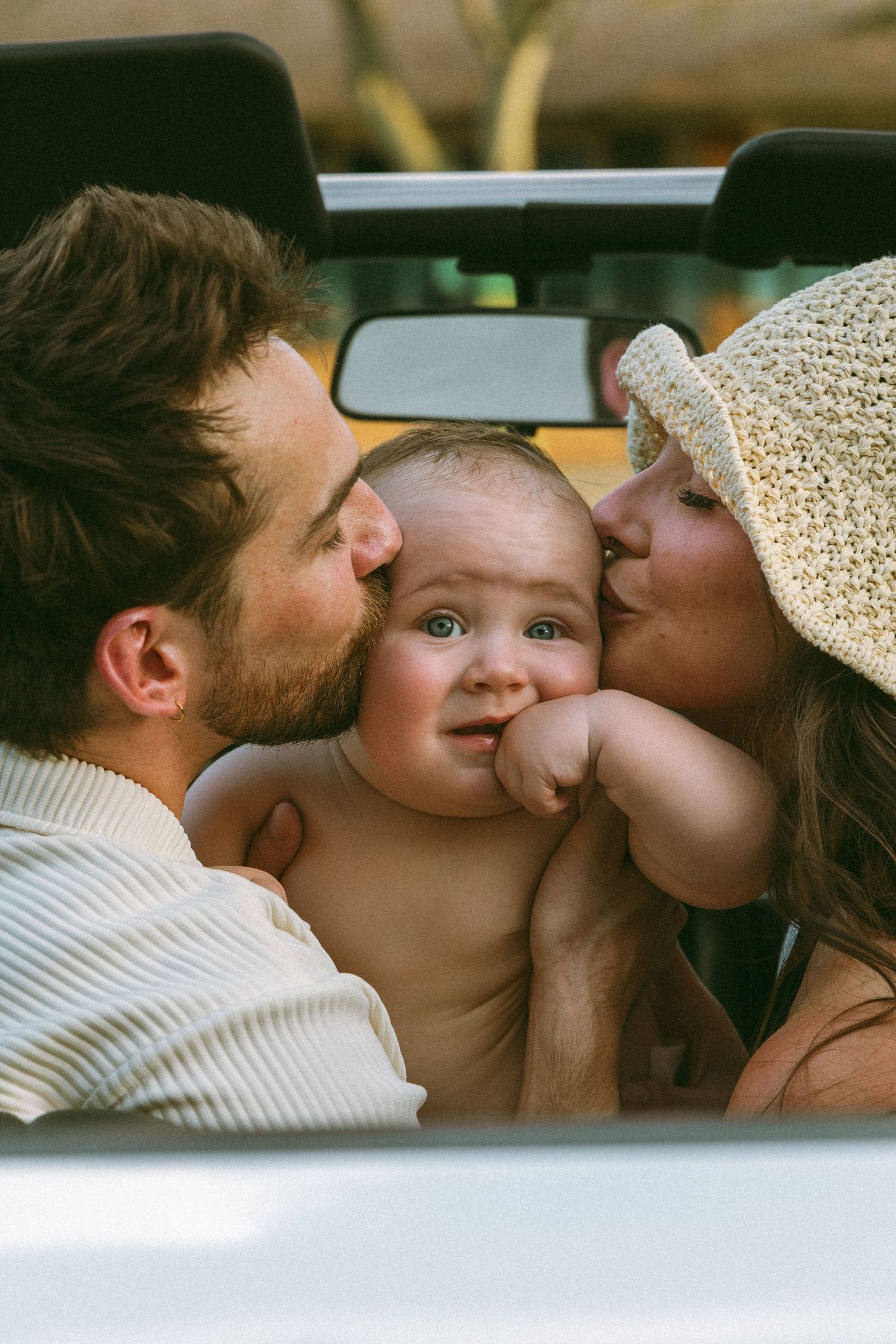 mother and father kissing son's head