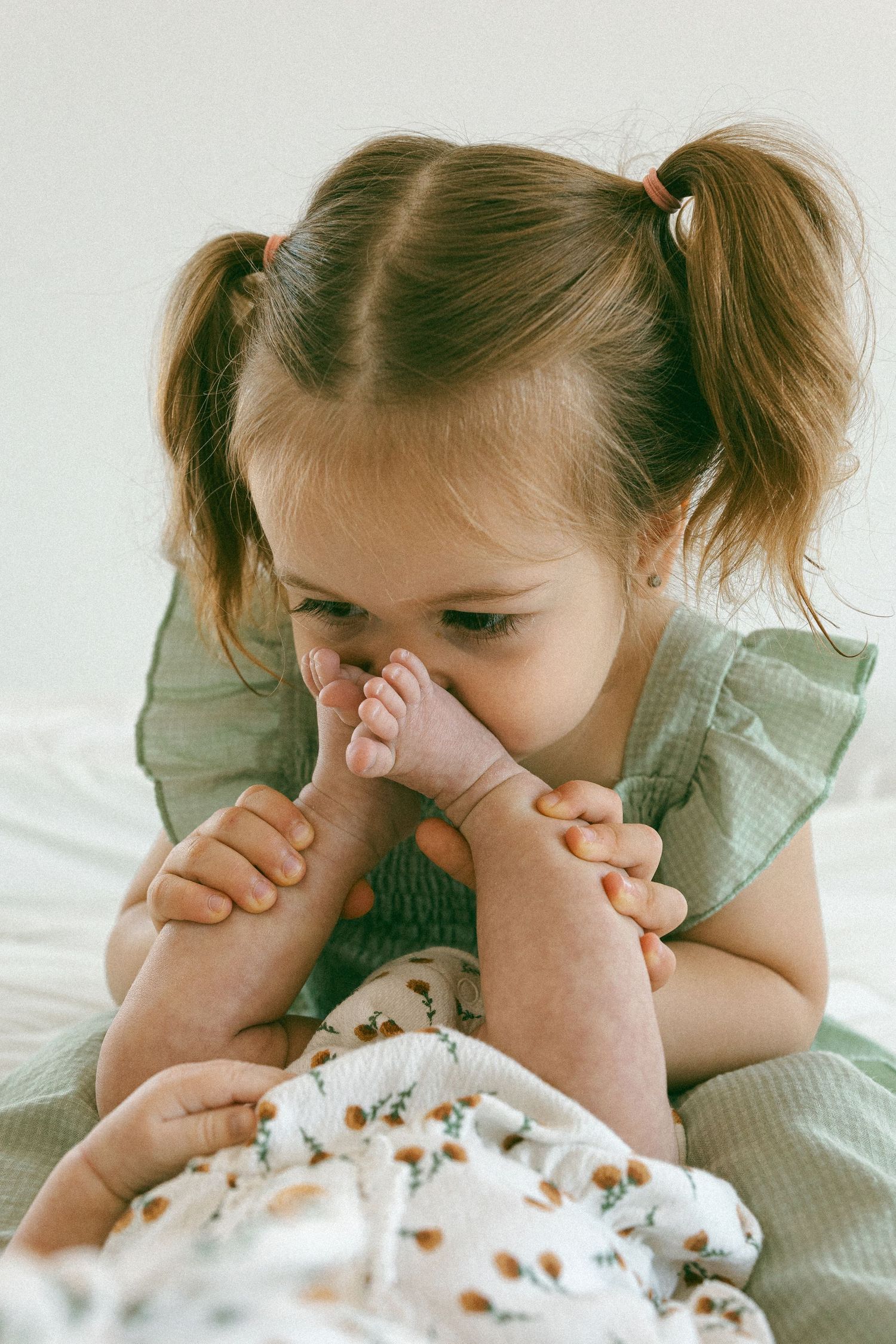 toddler smelling newborn baby feet