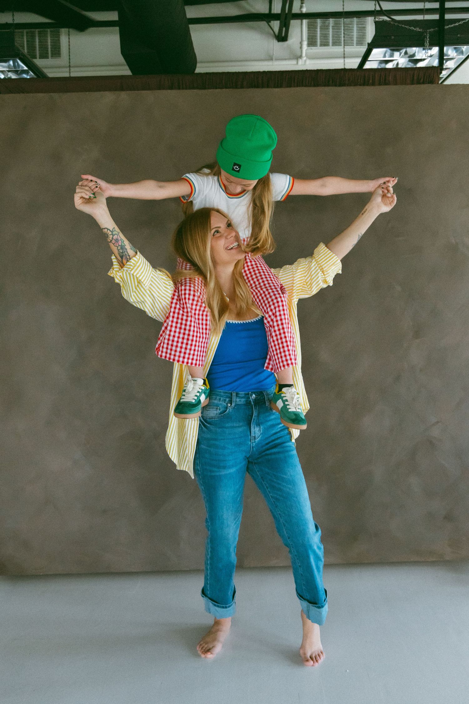 mother holding daughter on her shoulders during a studio session