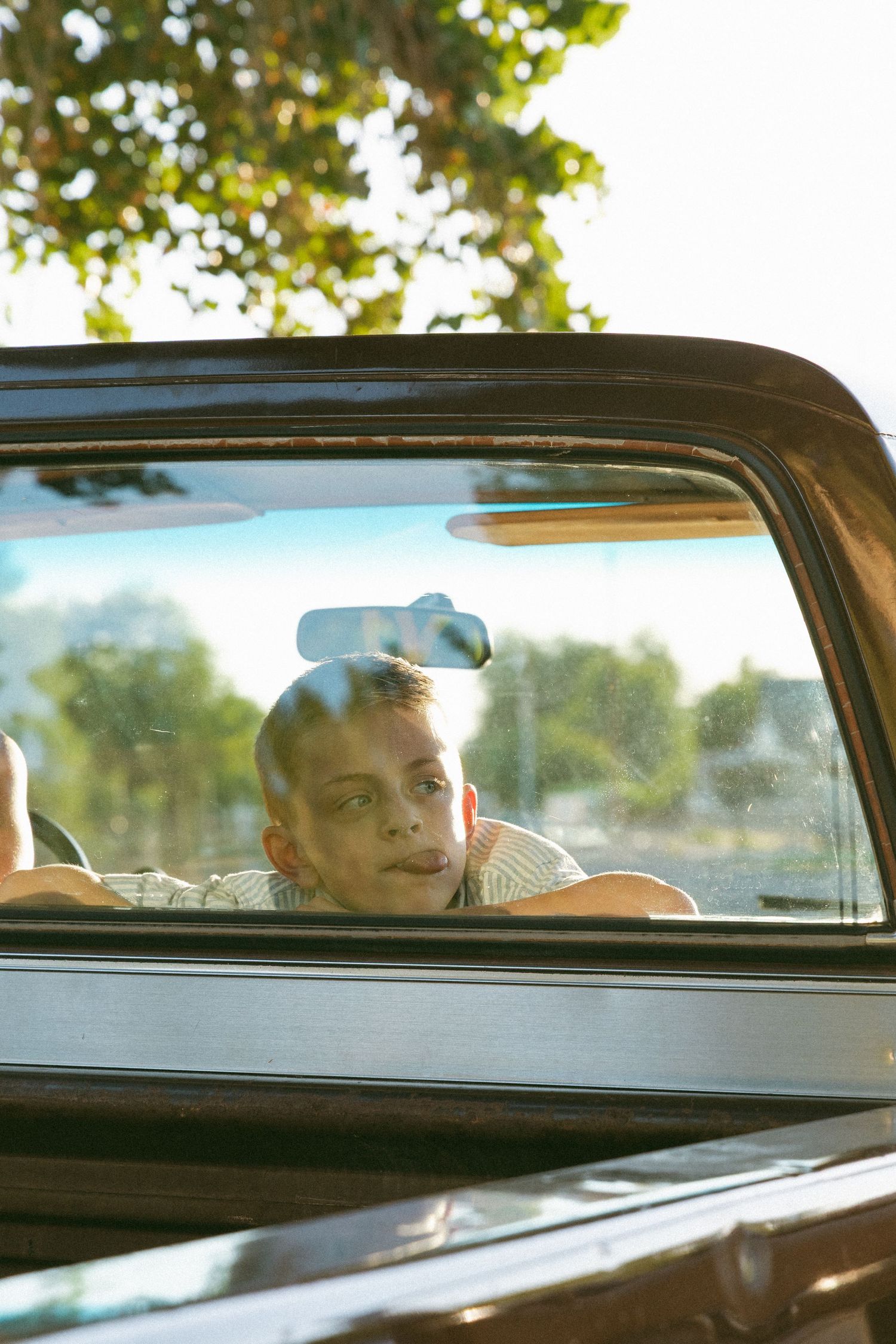 child being playful in the cab of an old truck