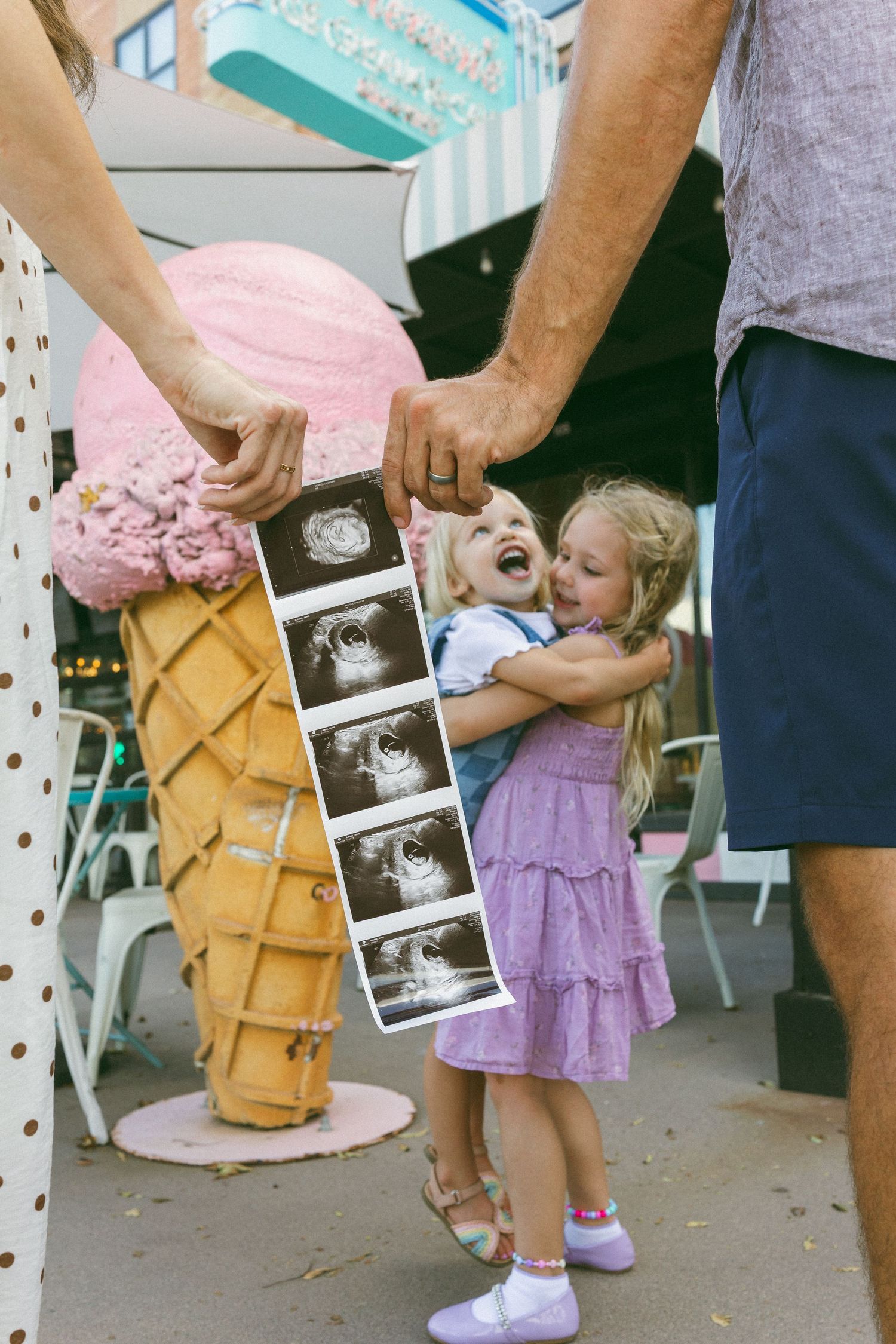 pregnancy announcement with two young girls embracing