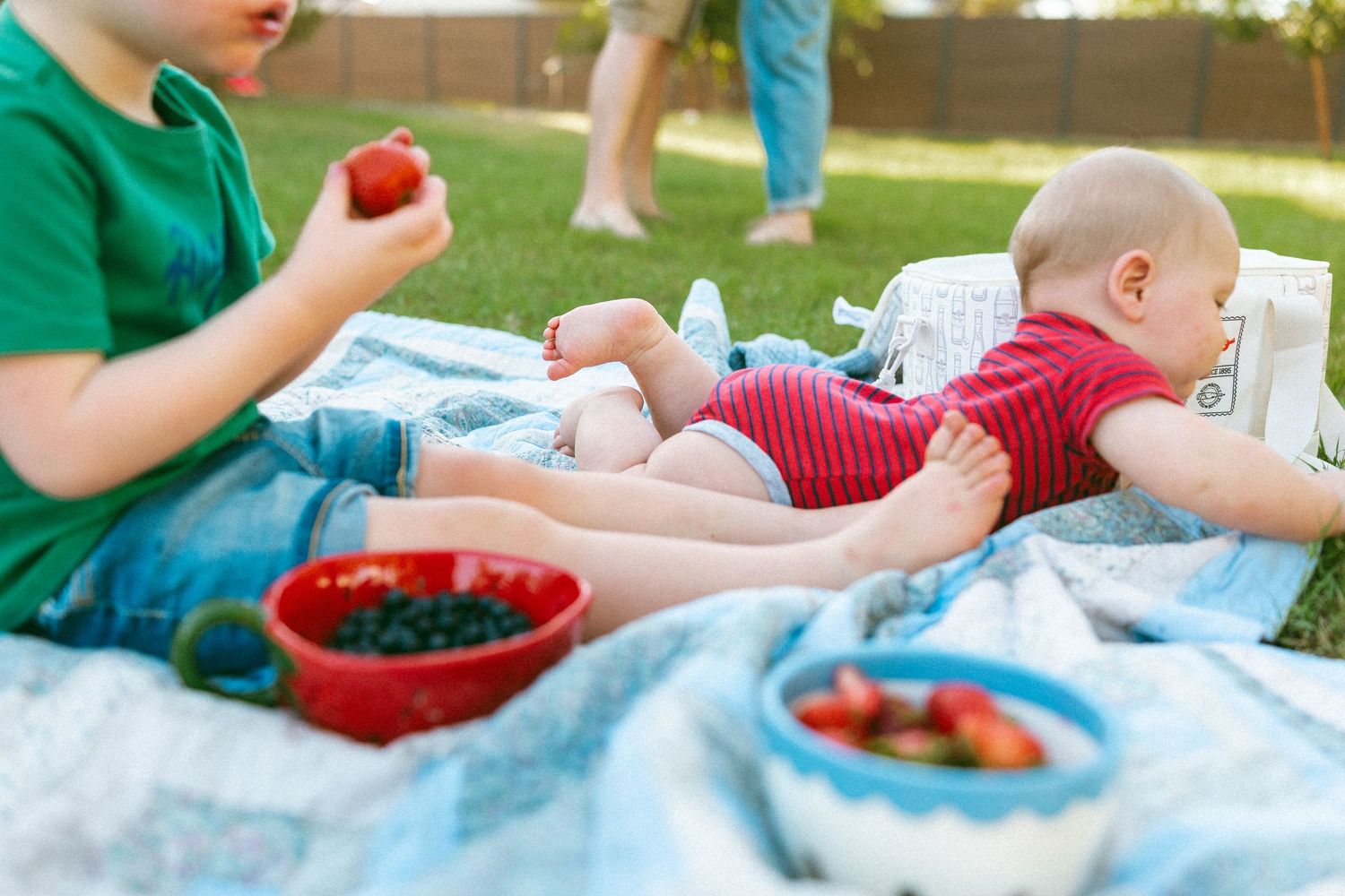 two kids laying on blanket eating berries during a family session