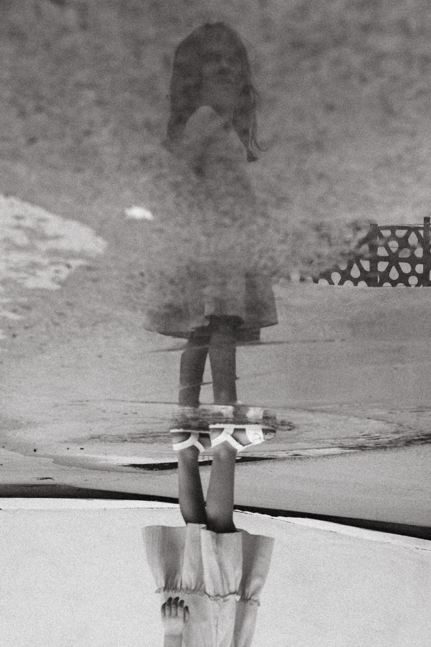 young girl standing in a puddle with her reflection