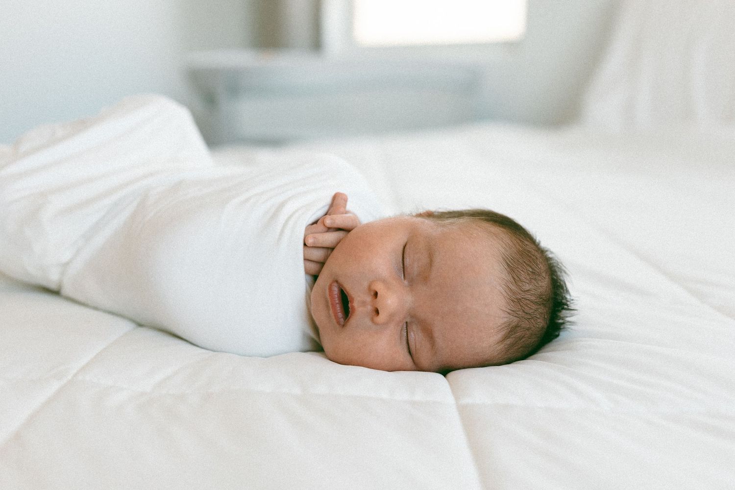 newborn baby sleeping on a bed during a lifestyle session