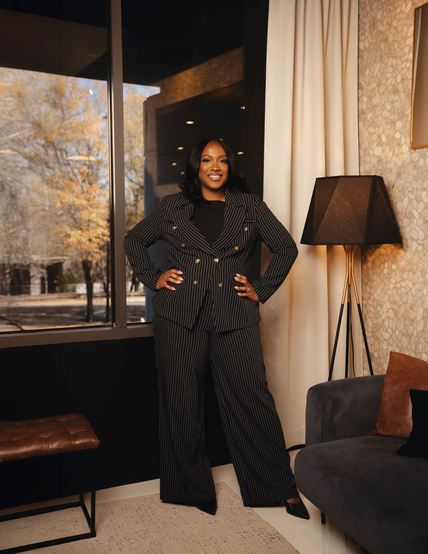 Atlanta business branding photography of a confident woman in a pinstripe pantsuit posing in a modern interior.