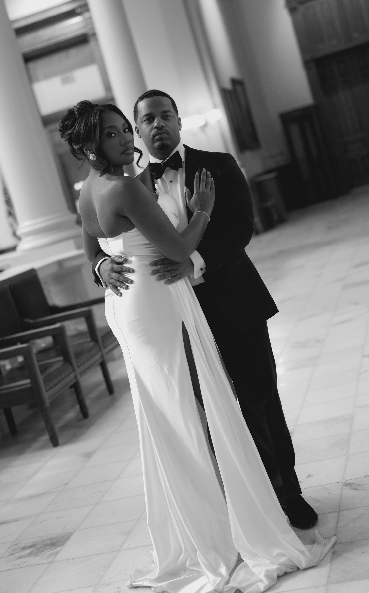 Black-and-white Atlanta wedding portrait of a bride and groom embracing in an elegant marble interior.