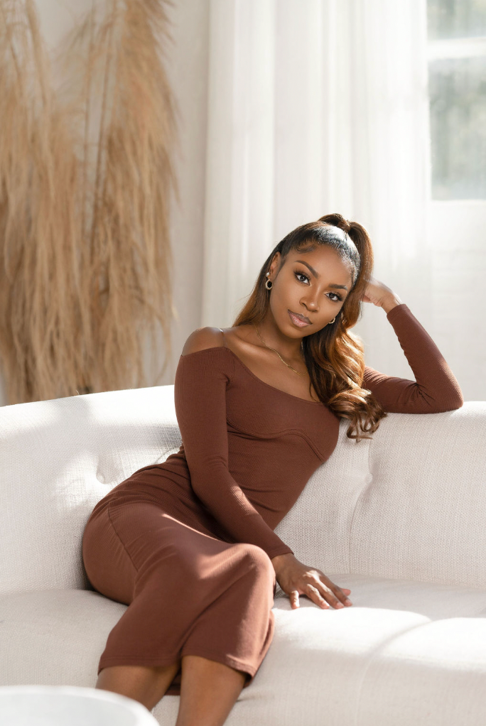 Atlanta portrait photography of a woman in a brown off-shoulder outfit posing on a white sofa in a bright stud