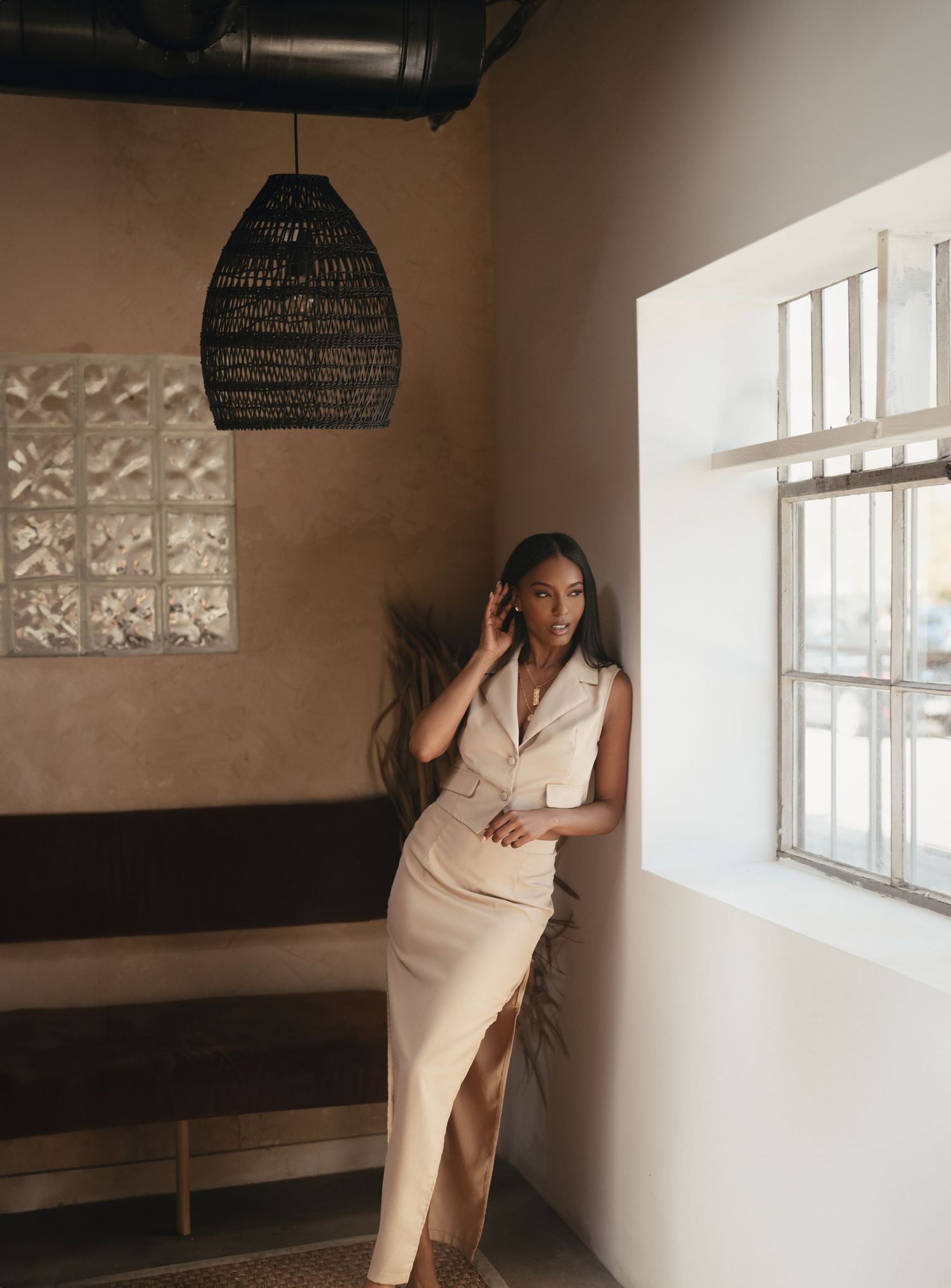 Atlanta business branding portrait of a woman in a beige blazer dress posing beside a window in a warm interior.