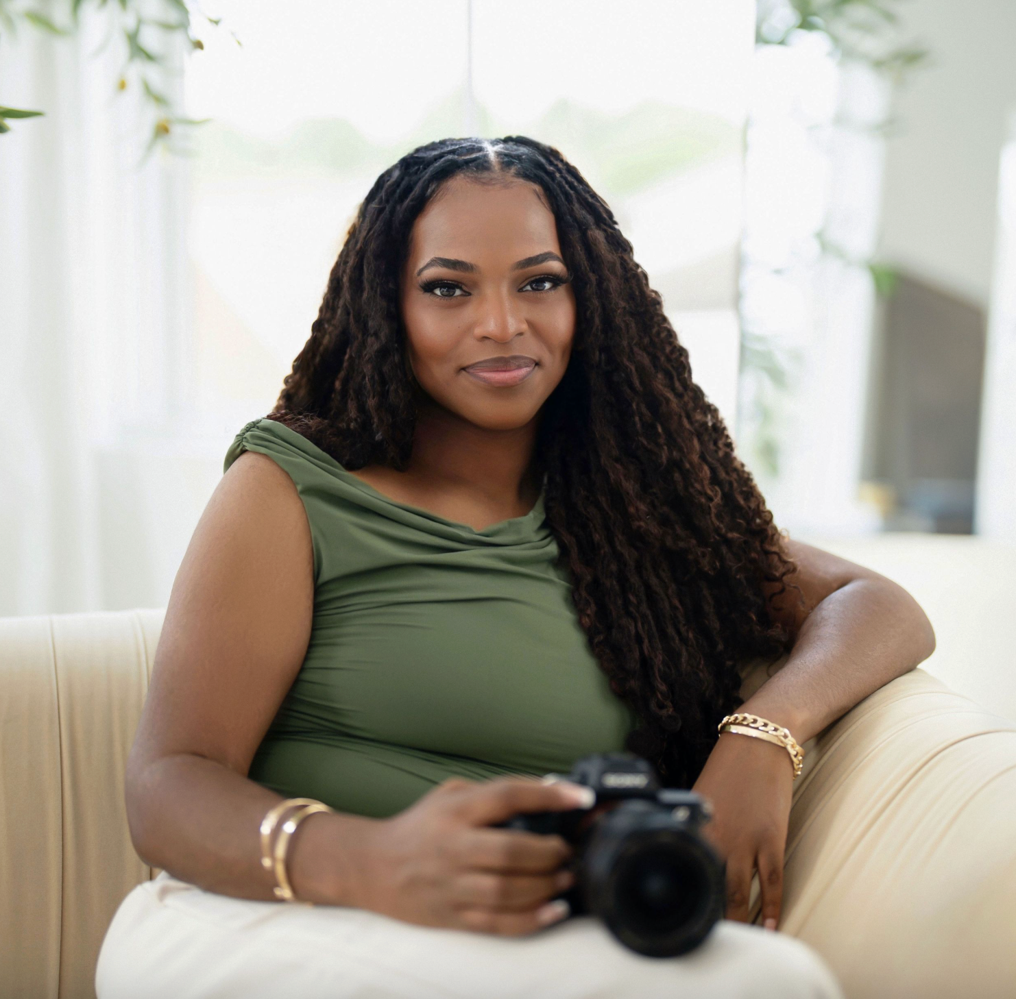 Atlanta photographer Nina of New Captures Photography seated with her camera in a bright studio setting.