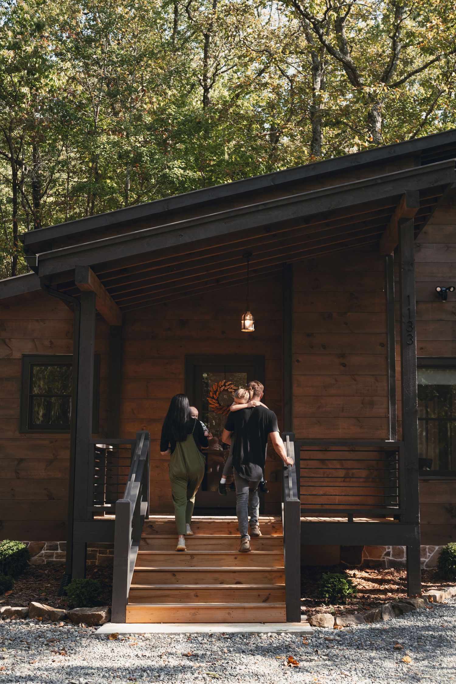 Atlanta-area family photography of a family arriving at a rustic cabin surrounded by autumn trees.