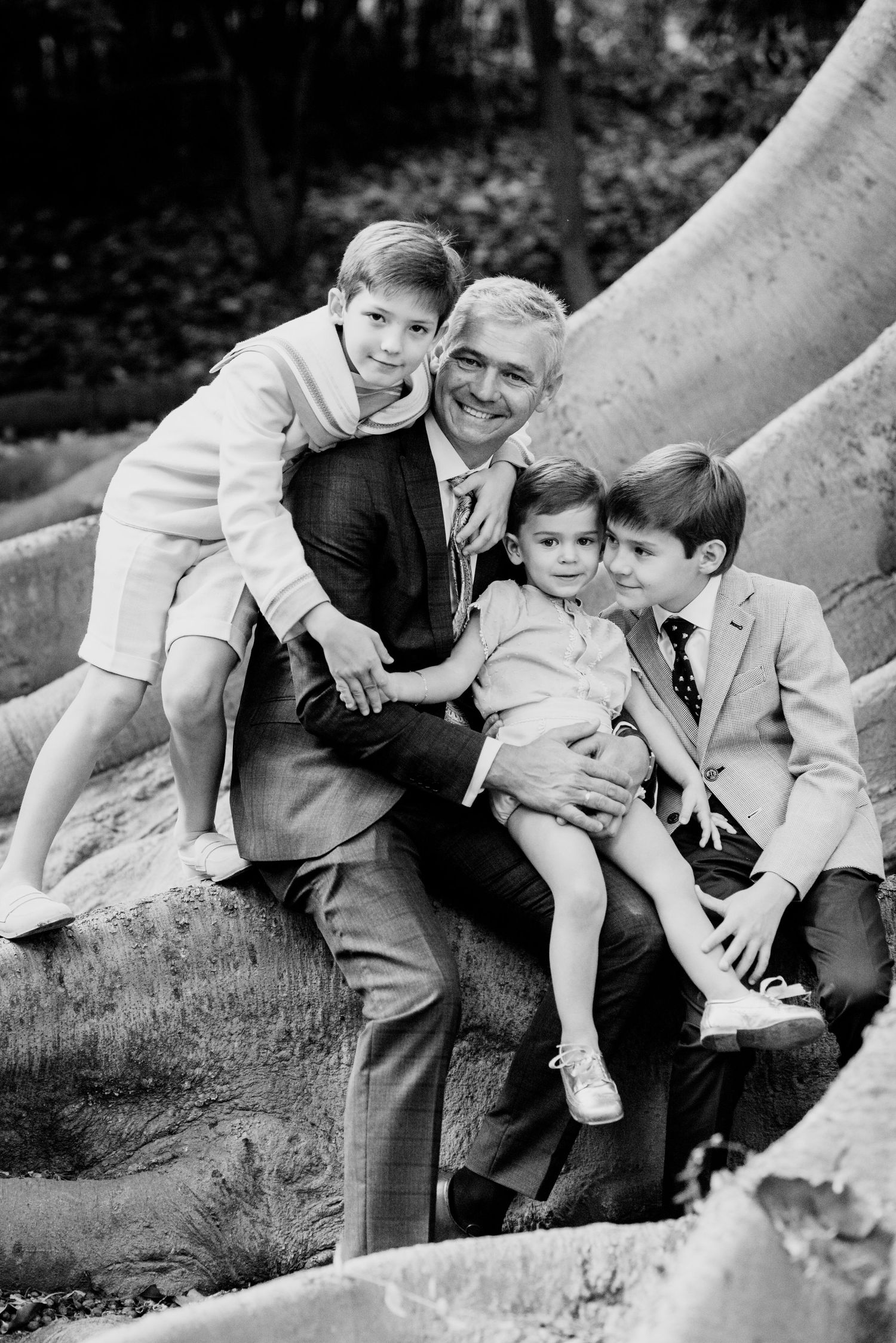 Black and white photo of father with three children outdoors.