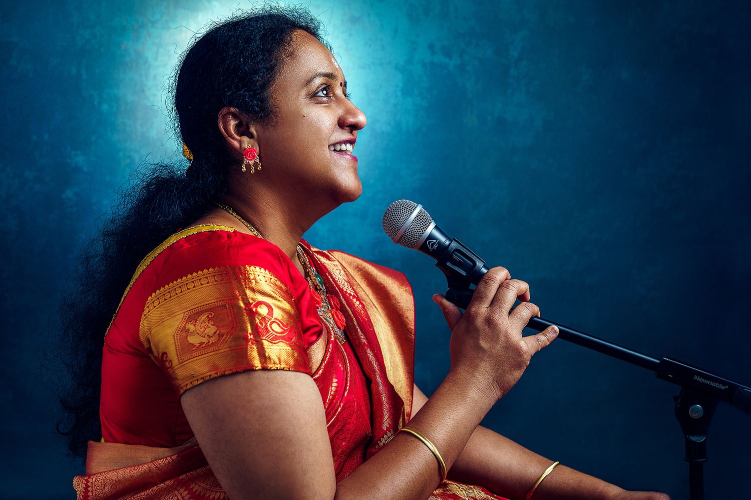 Singer performing with microphone against blue studio backdrop.