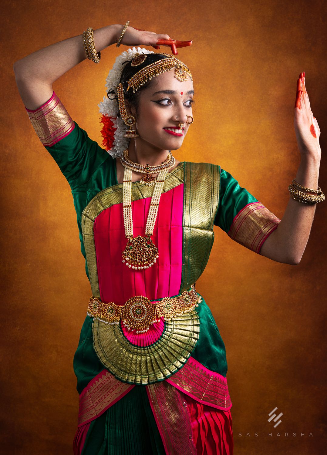 Woman in traditional Indian dance attire striking a pose, showcasing intricate jewelry and vibrant clothing