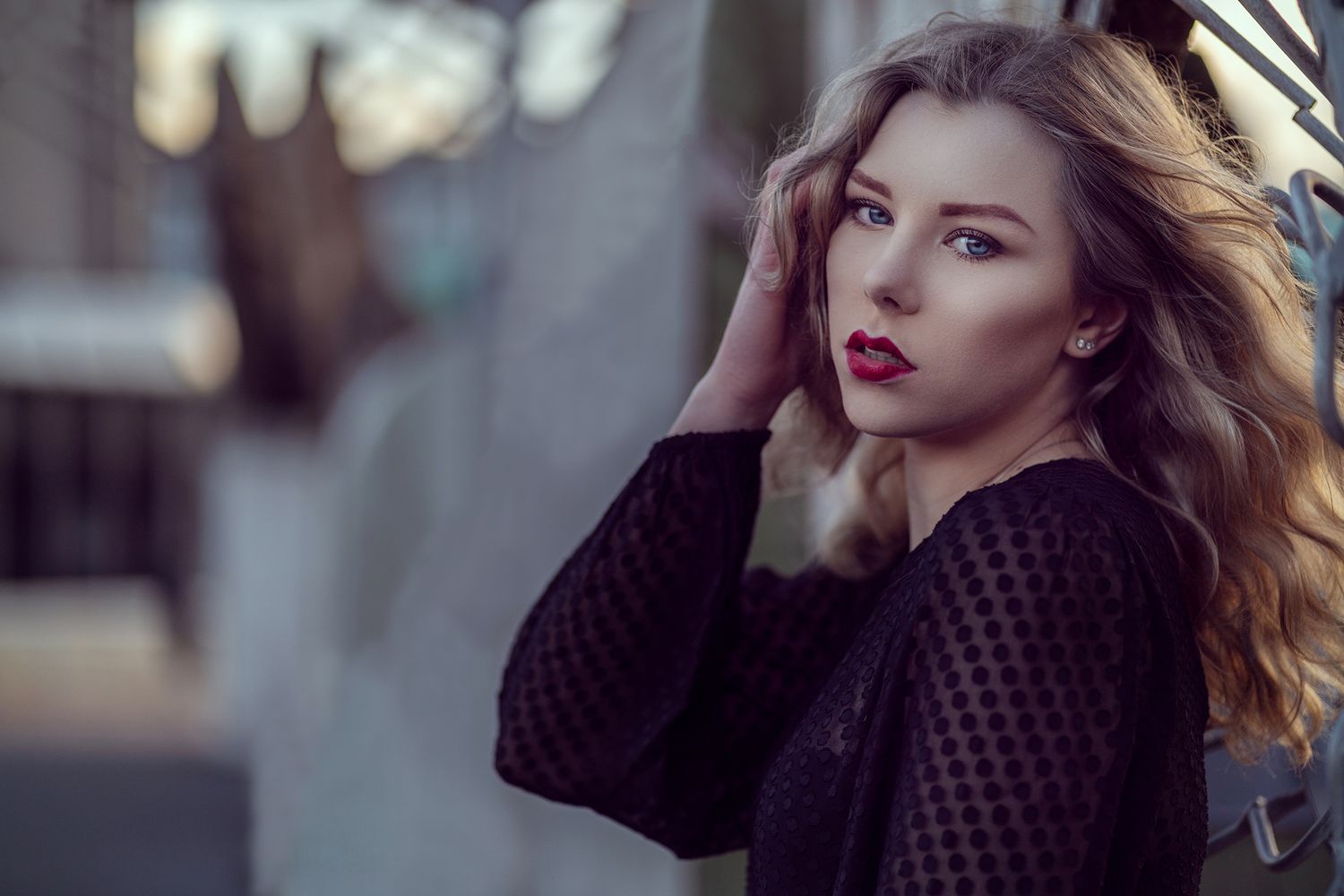 Woman with windswept hair posing in urban setting during golden hour.