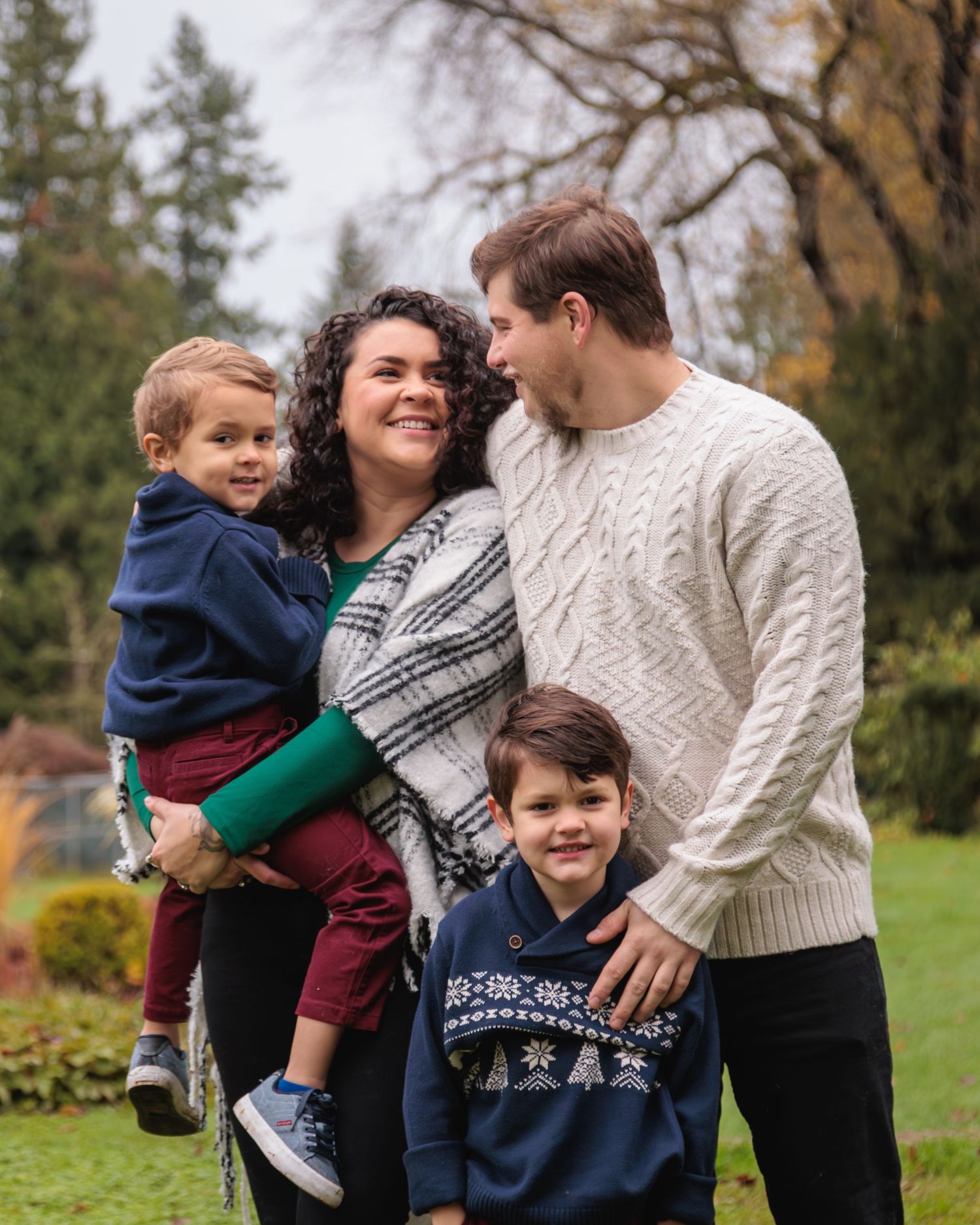 A father, mother, and two sons laughing together between poses during a Family Session.
