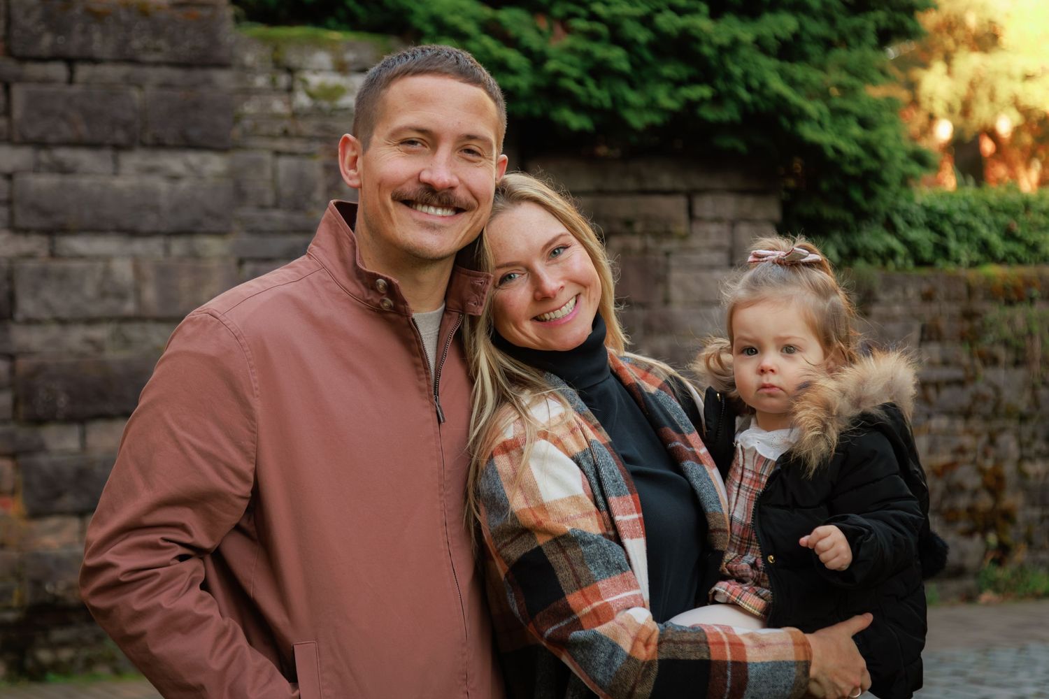 A family of four shares laughter outdoors, surrounded by nature, enjoying a joyful and candid moment together.
