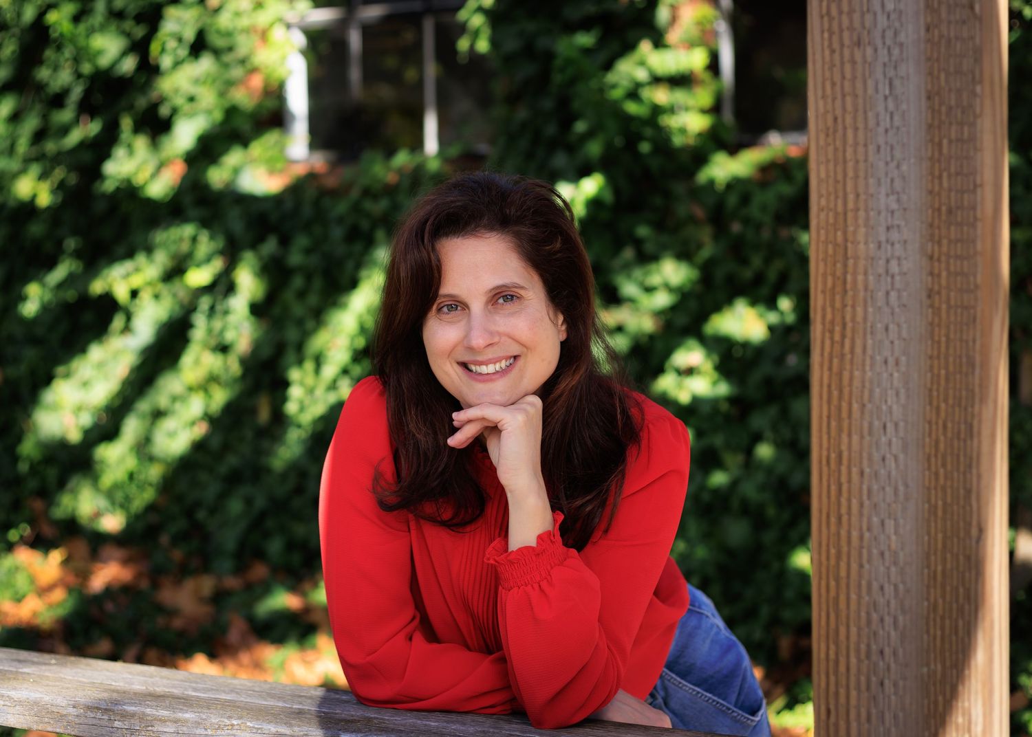 Headshot photo of a woman leaning on a fence.
