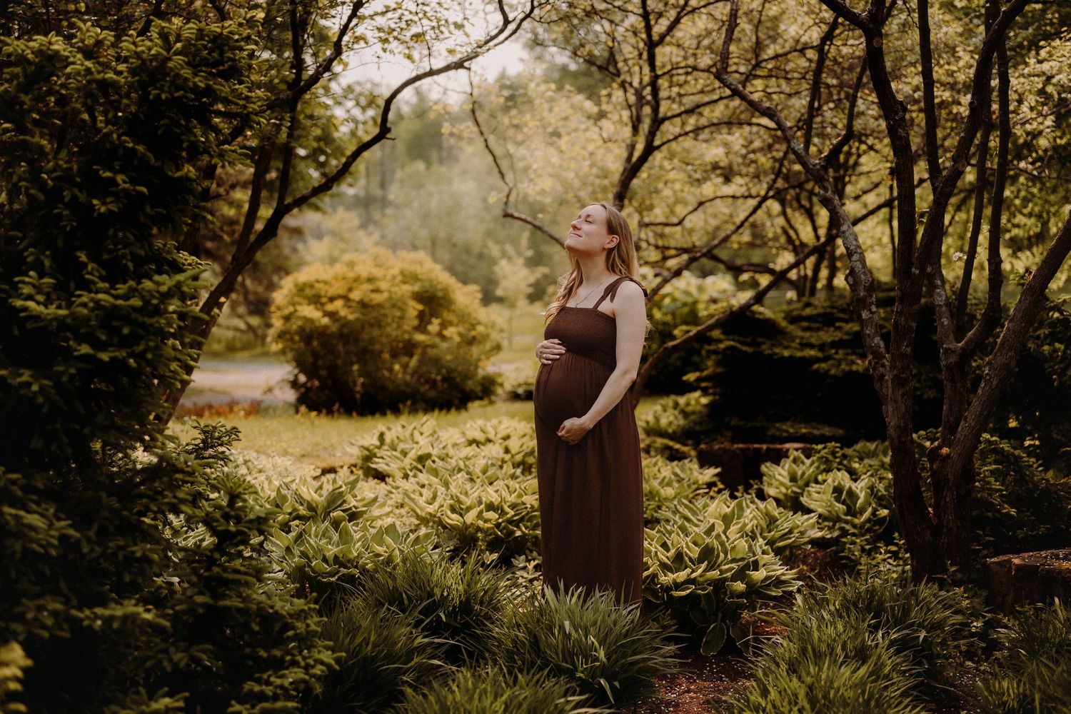 Atmospheric woodland photography session captured in golden hour sunlight through lush forest foliage.