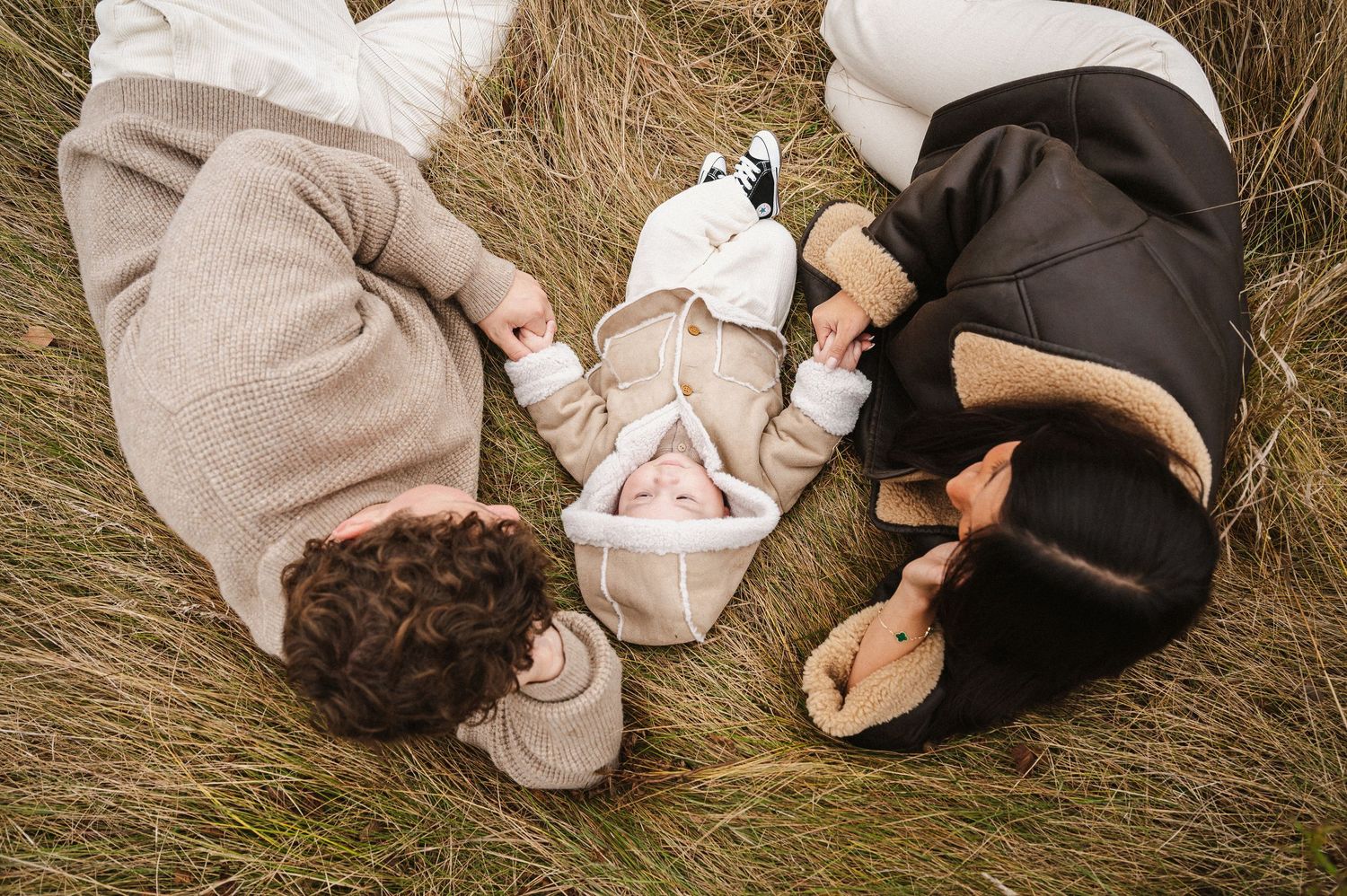 A couple lying in tall grass together during an intimate outdoor photo session.