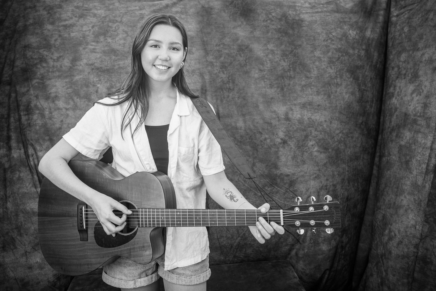 Musicians performing with acoustic guitars against a dark background in black and white.