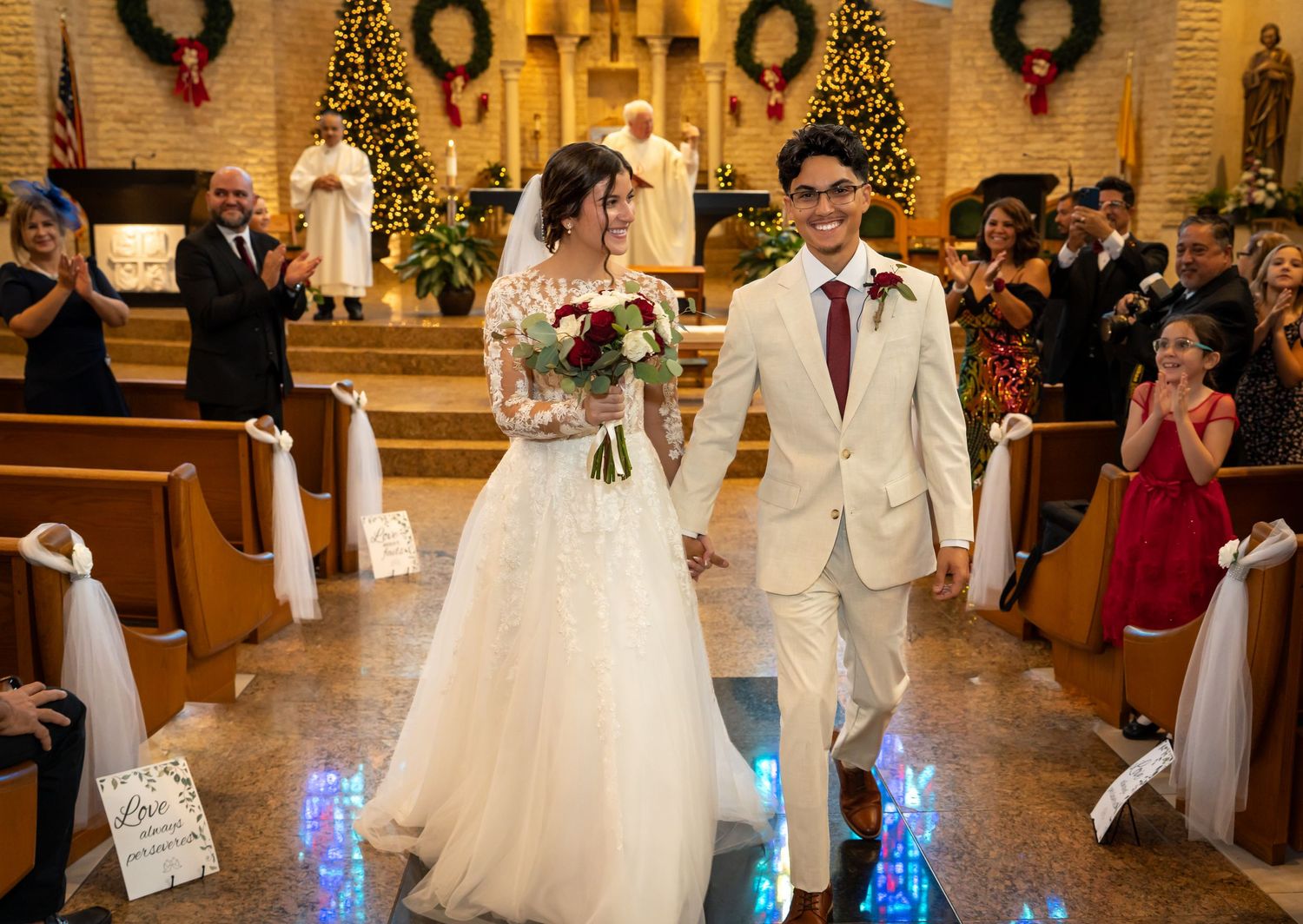 Newlywed couple walks down church aisle with blue LED lights and holiday decorations in elegant ceremony.