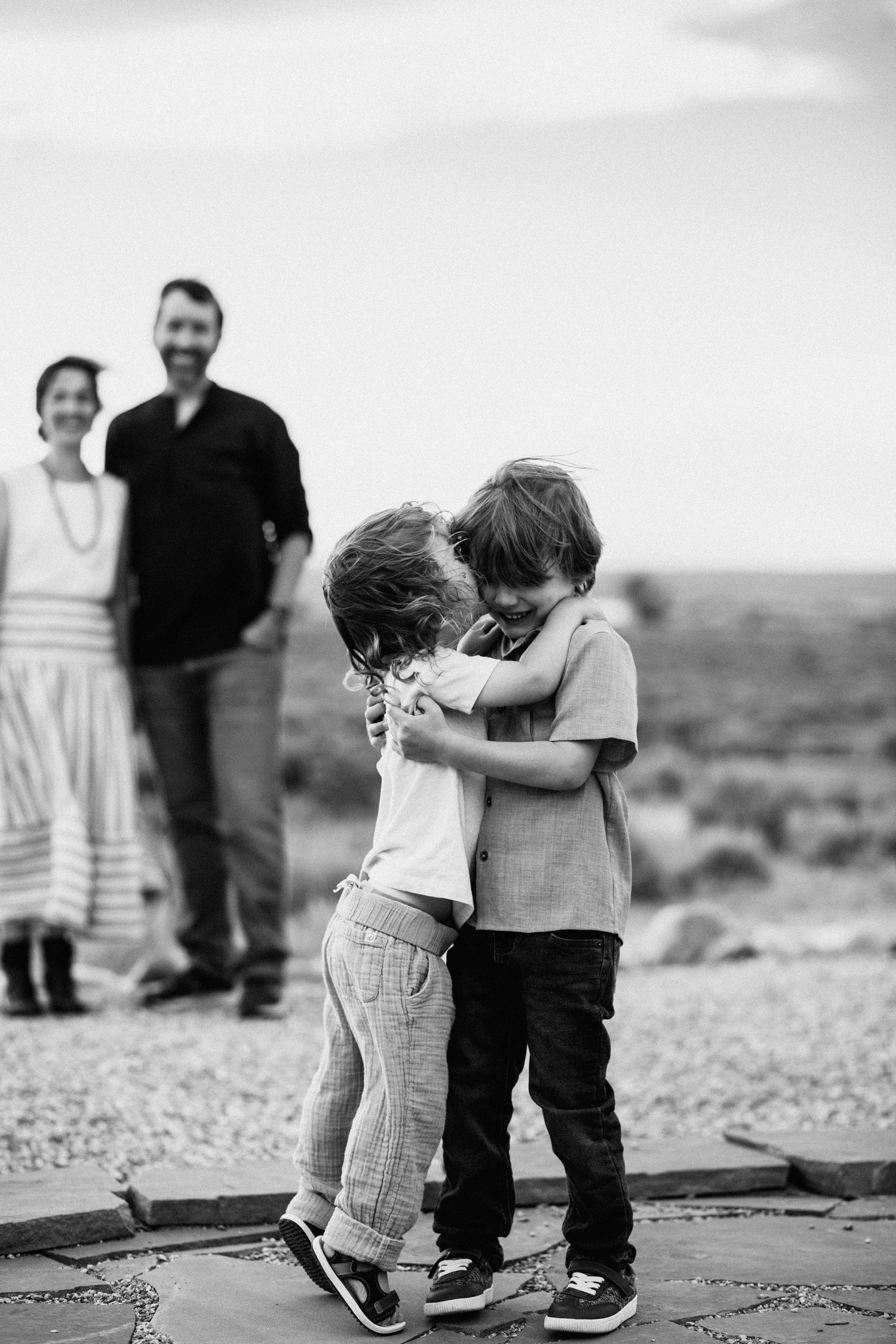 Children playing and jumping on concrete surface in black and white.  Shot in Taos, NM by Siouxzen Kang