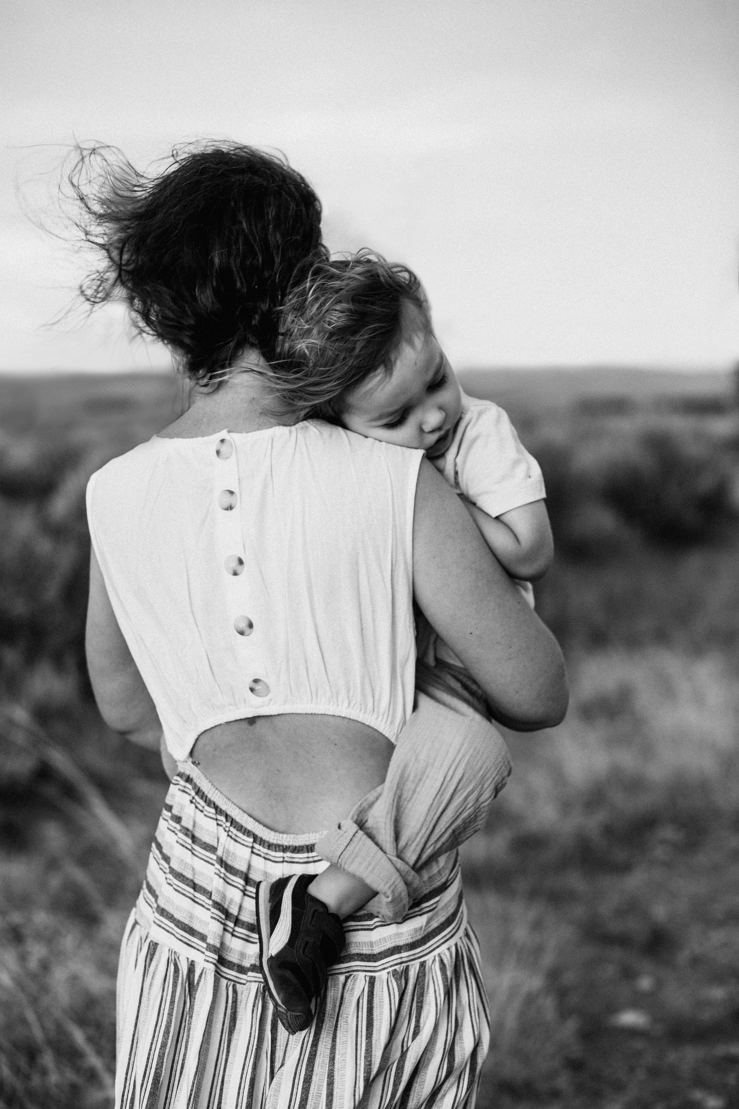 Close-up of a tender embrace between two people wearing summer clothing outdoors.