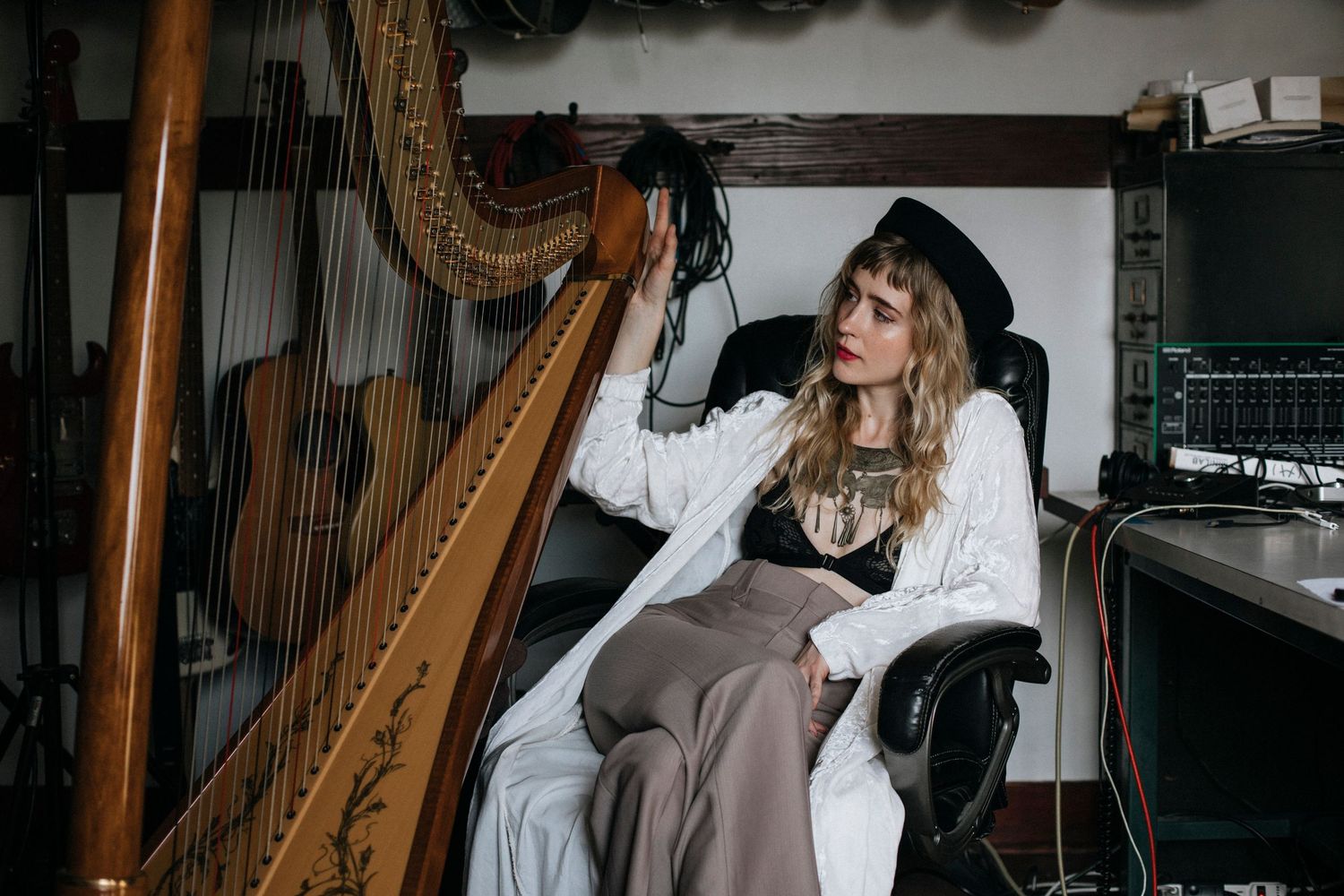 Artistic portrait with vintage harp and white lace clothing in atmospheric indoor setting.