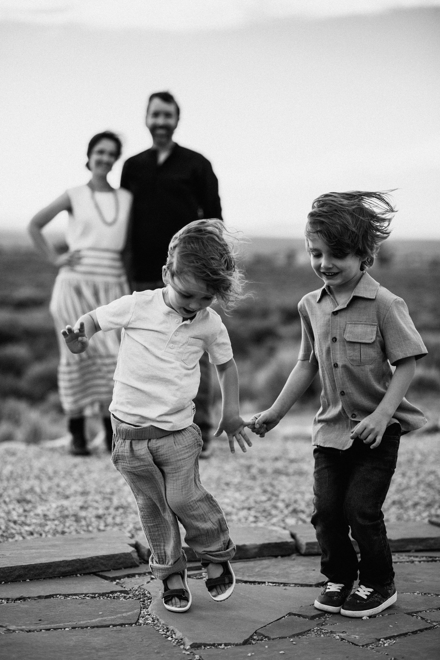 Children jumping and playing on a paved path in black and white.