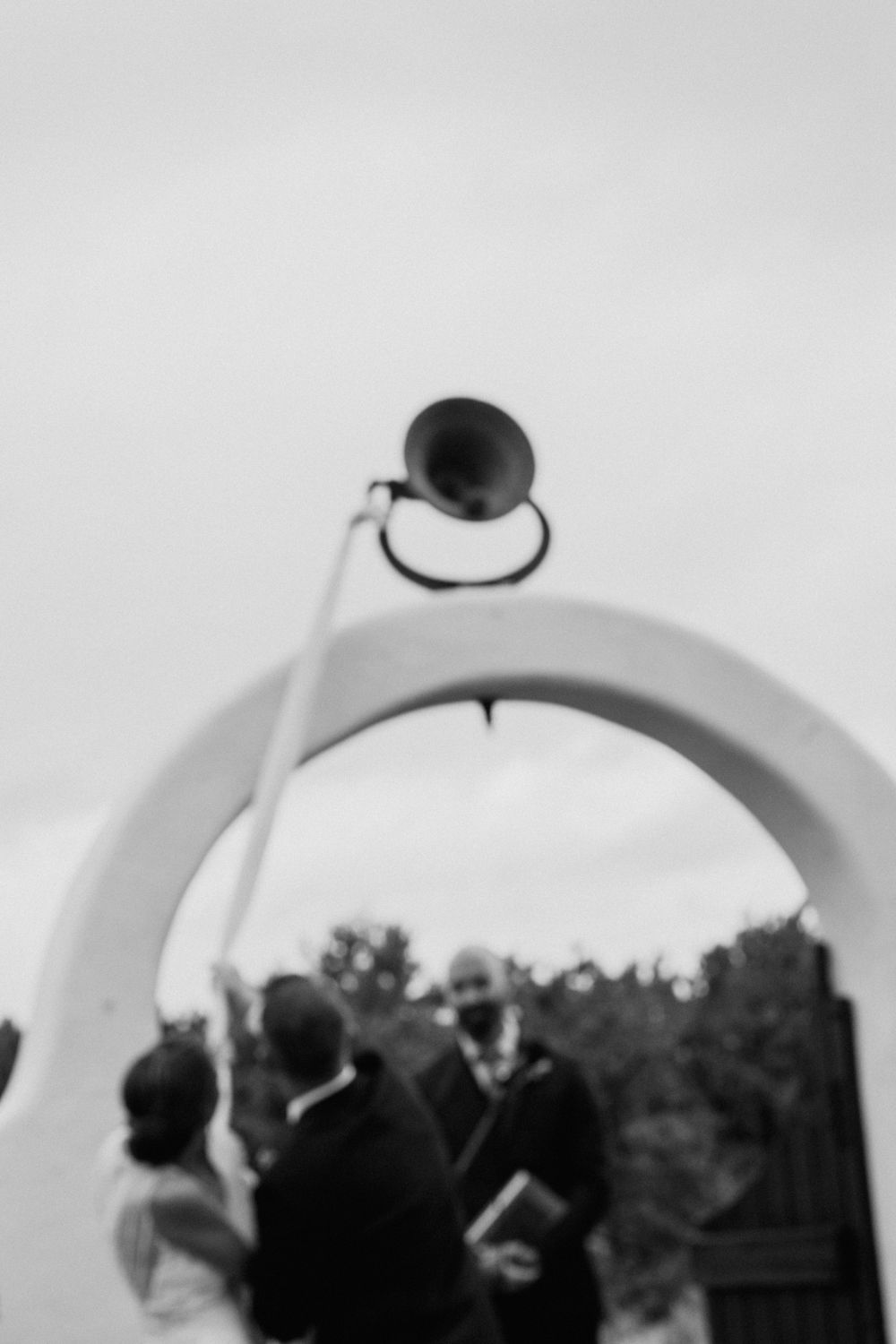Black and white photo of a wedding ceremony viewed through a curved archway.