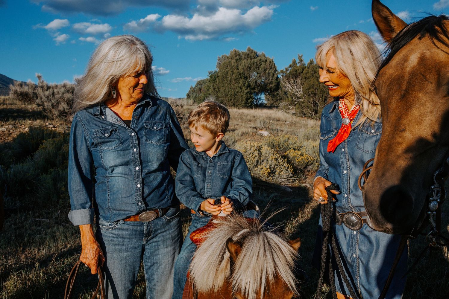 Grandmothers interacting with grandson during a family session in Taos, New Mexico with a horse and mountain landscape in the background