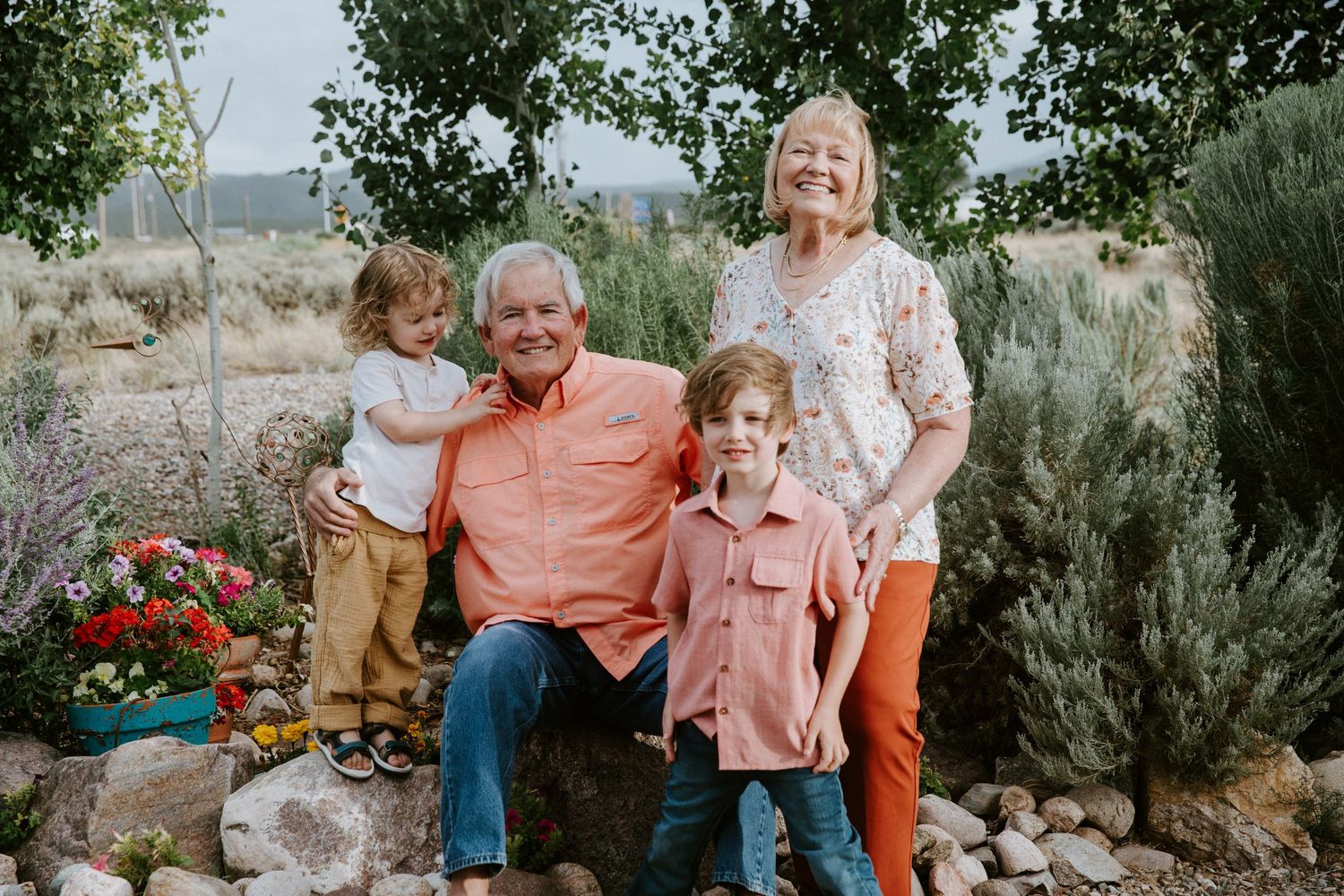 Family group poses together in natural desert landscape with greenery and rocks.