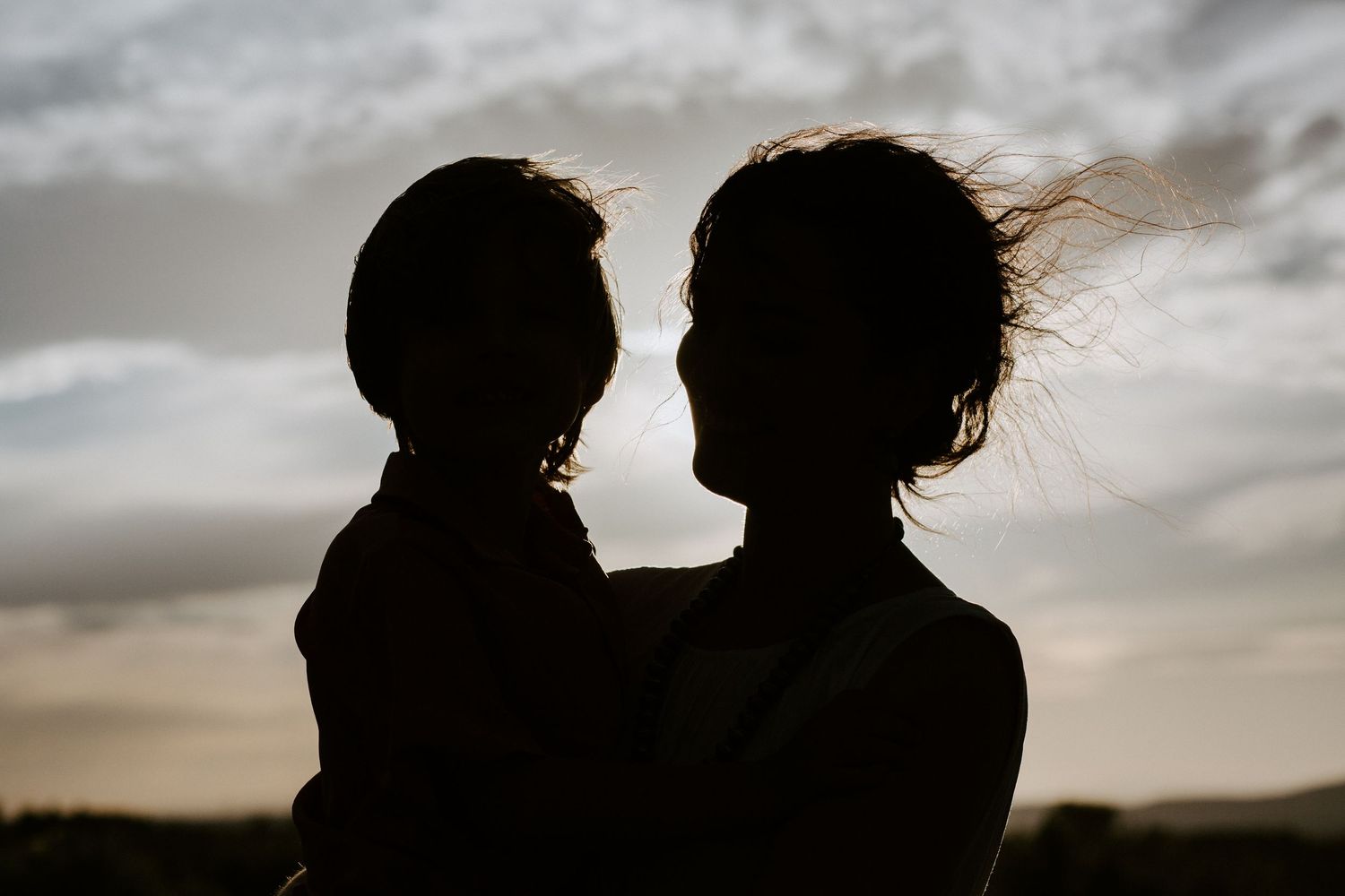 Silhouetted figures against dramatic cloudy sky showing intimate moments and embraces.