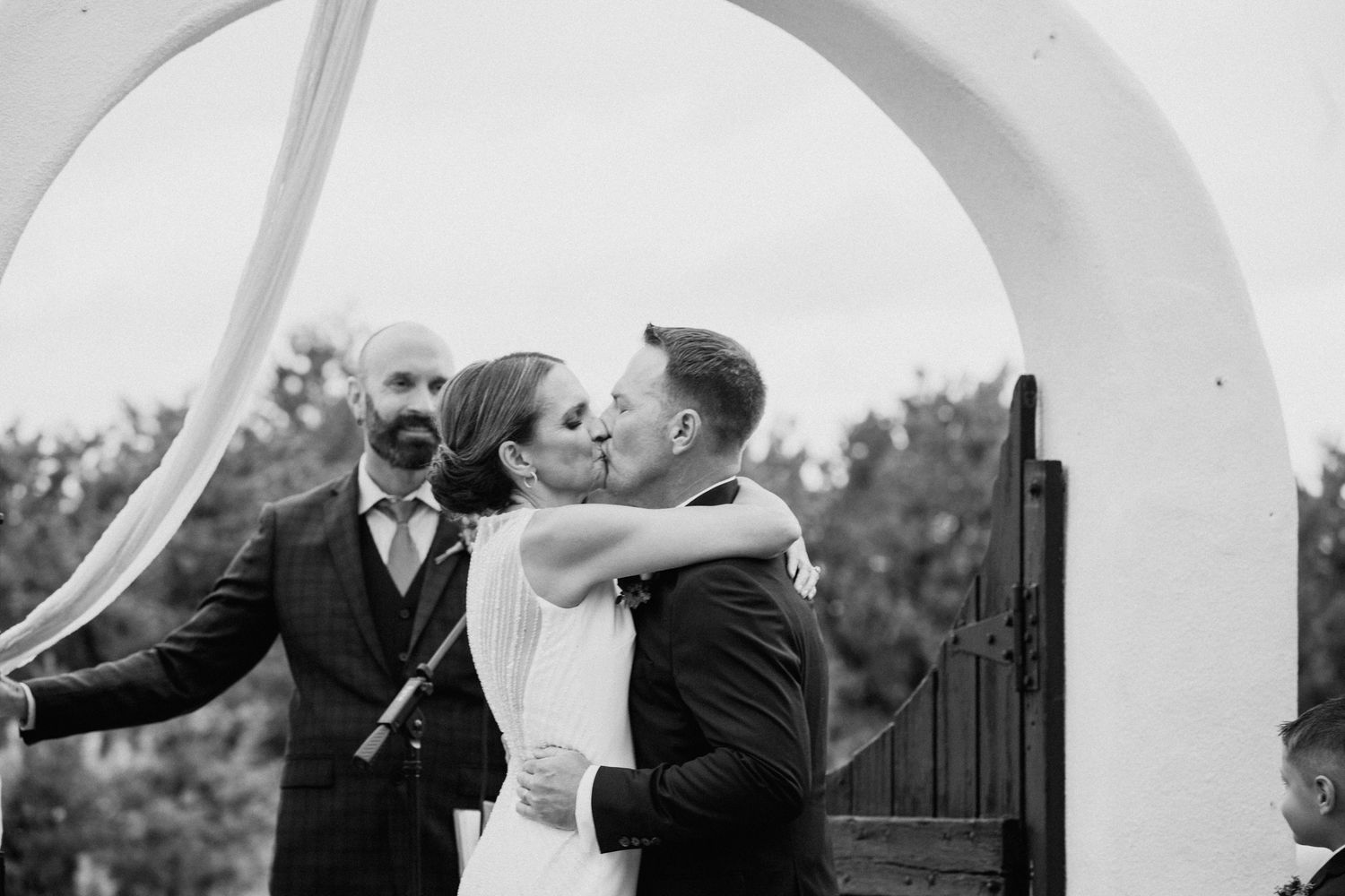 Romantic black and white wedding photos captured under elegant white archways.