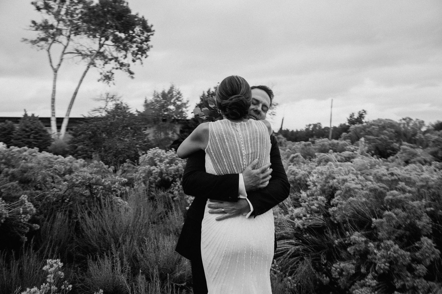 Black and white wedding photos show couple embracing in a garden setting with natural foliage and flowers.