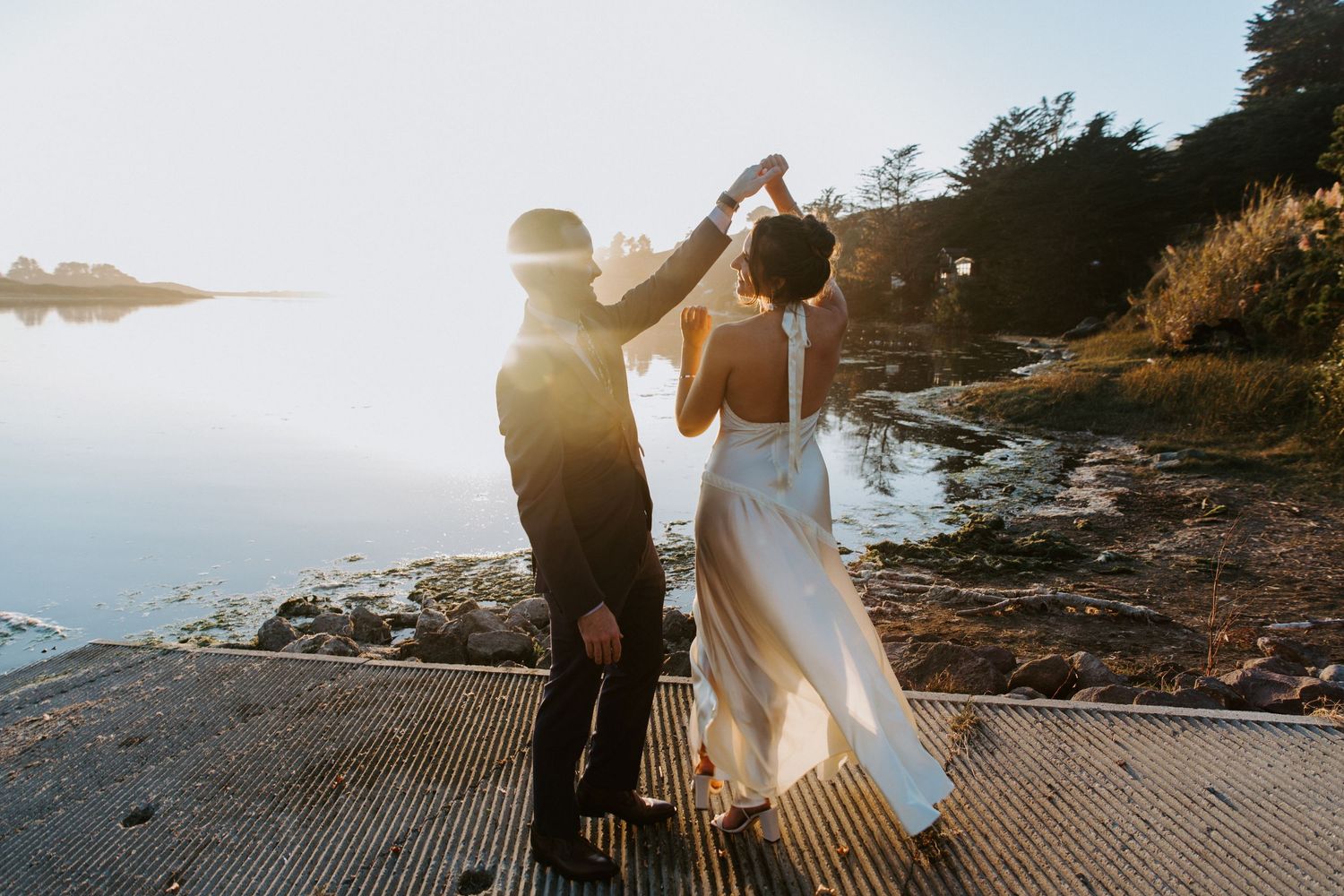 Couple shares romantic sunset dance on scenic coastal cliffside with ocean views.