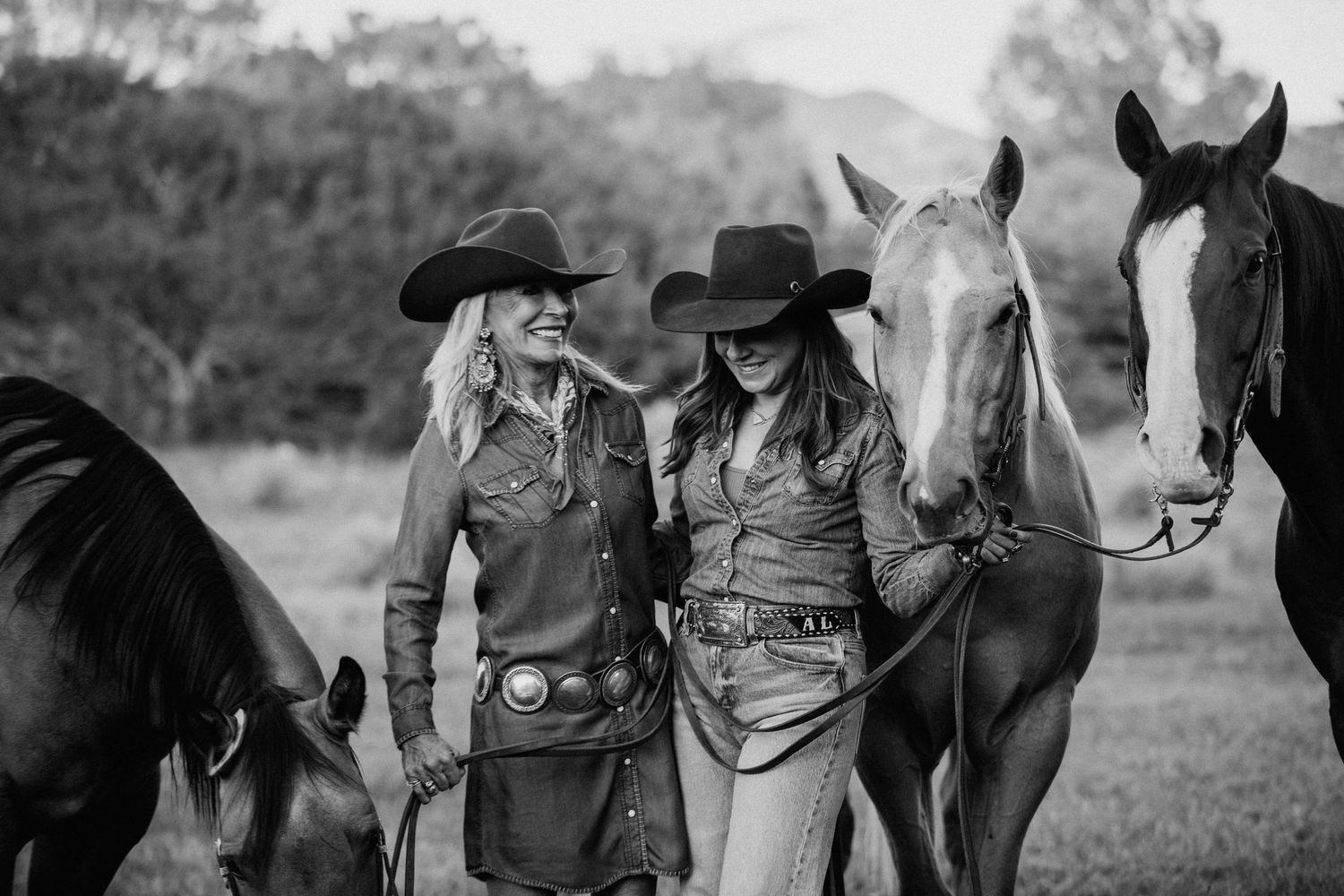 Black and white western lifestyle session in Taos, New Mexico with cowboys and horses against a mountain landscape
