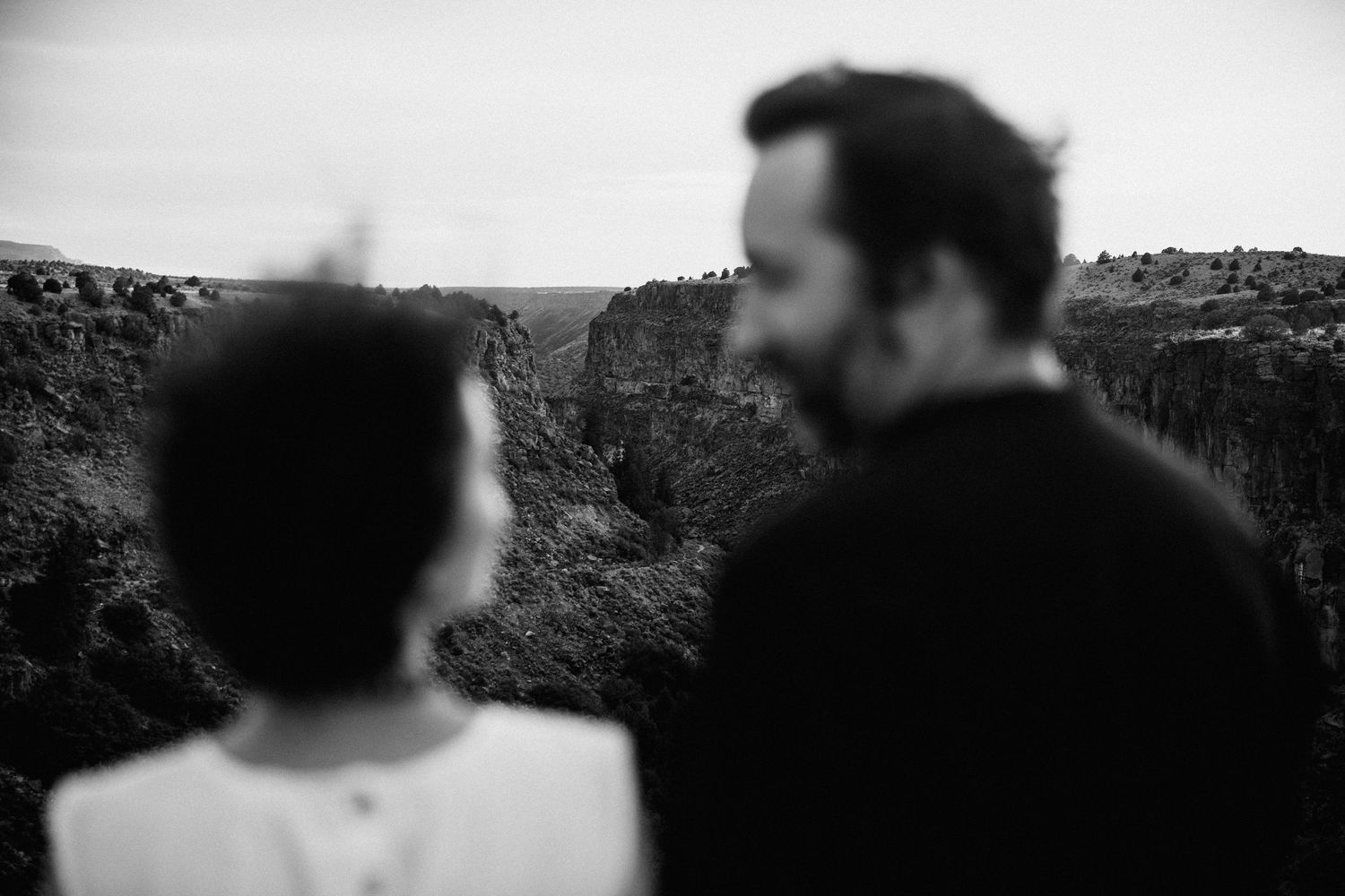 Silhouetted figures embrace against blurred natural landscape background.